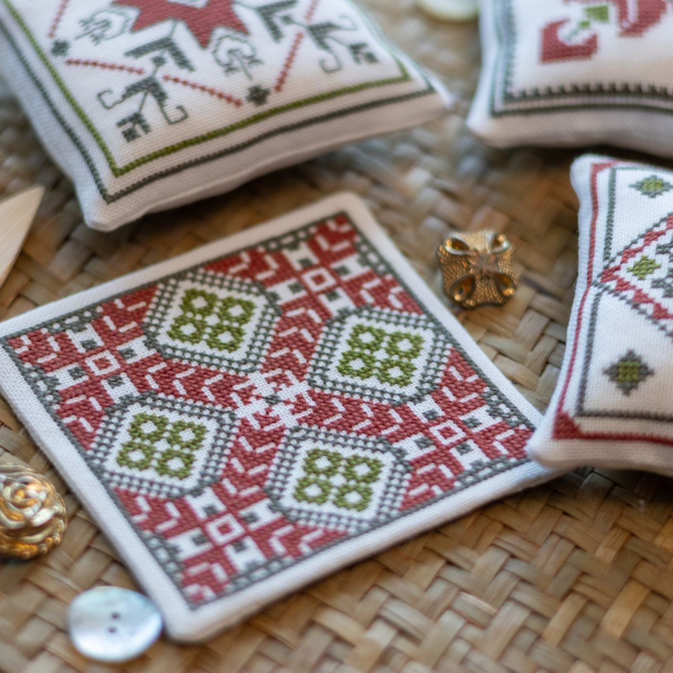 Decorative cross stitch ornaments with geometric patterns on a woven placemat