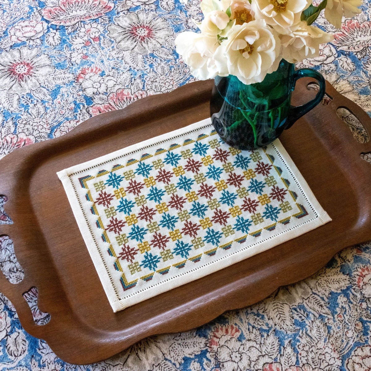 Anatolian Leaf and Knot cross stitch folk embroidery table runner laid on a table in copper and blue