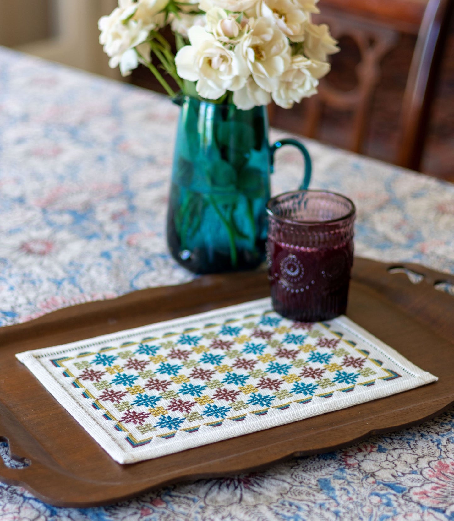 folk embroidery with repeating design in teal and burgundy