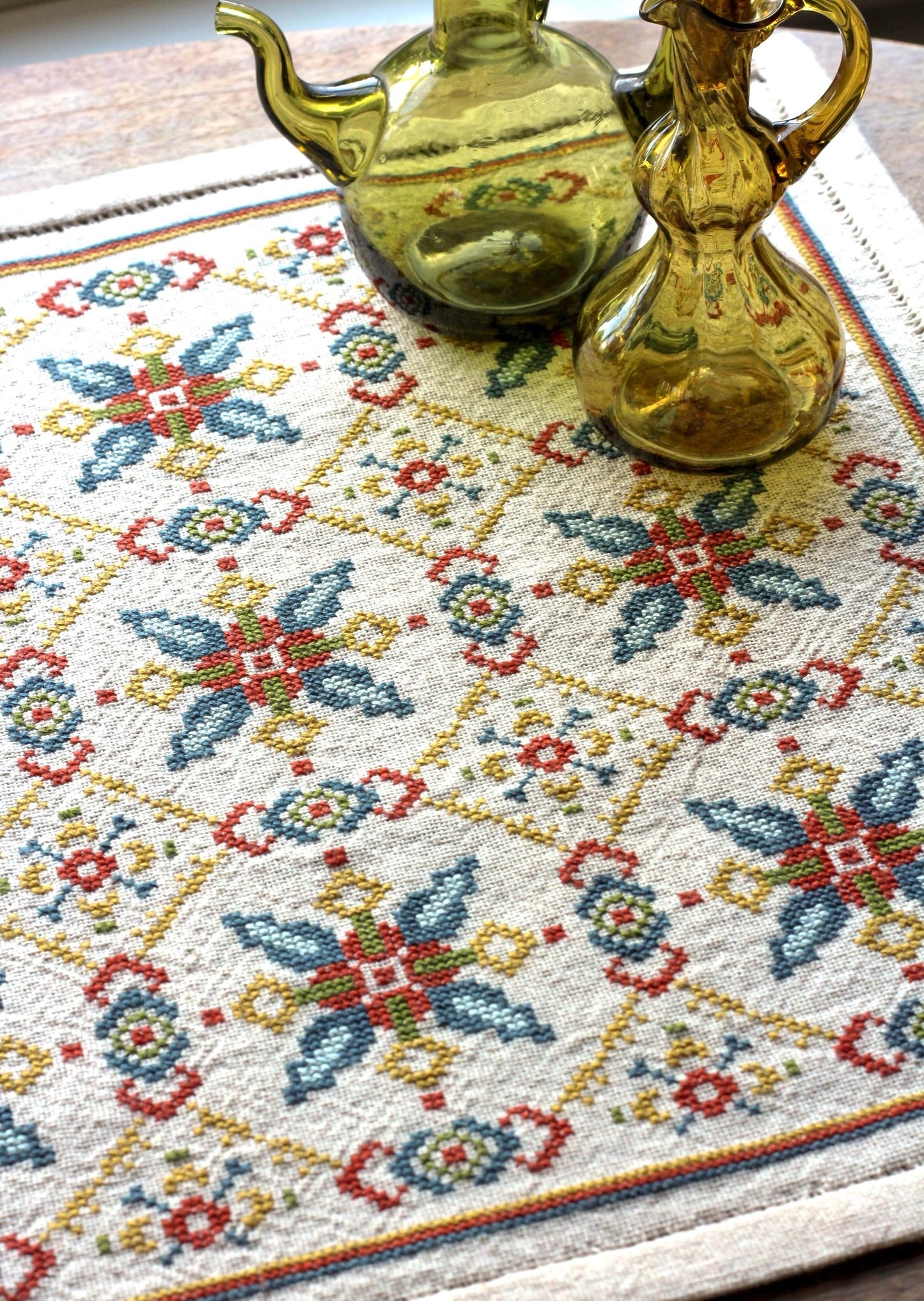 folk embroidery table runner with repeating star design in teal and terra cotta