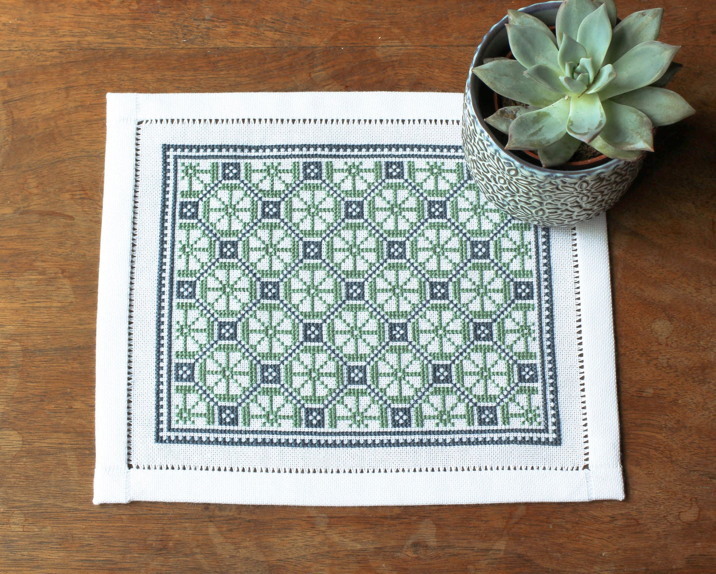 folk embroidery table mat with green and blue design and plant