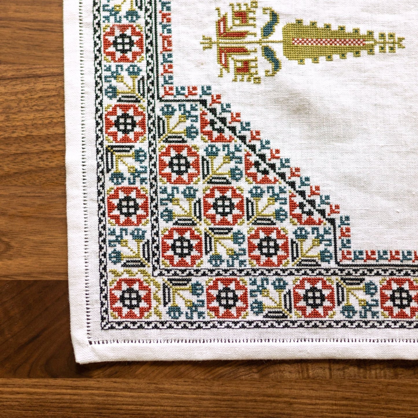 cross stitch folk embroidery table runner with stars, flowers, and cypress tree on white linen