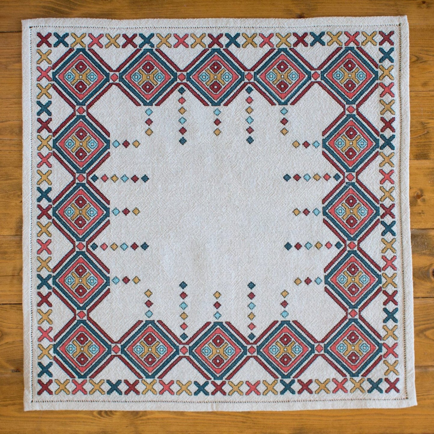 Embroidered quilt with geometric pattern on a wooden surface