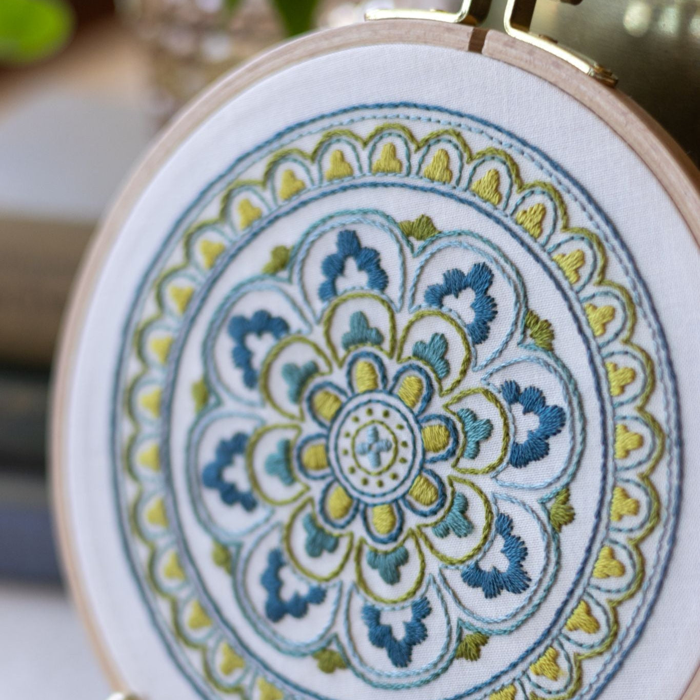 Embroidery hoop with a colorful mandala design on a white background