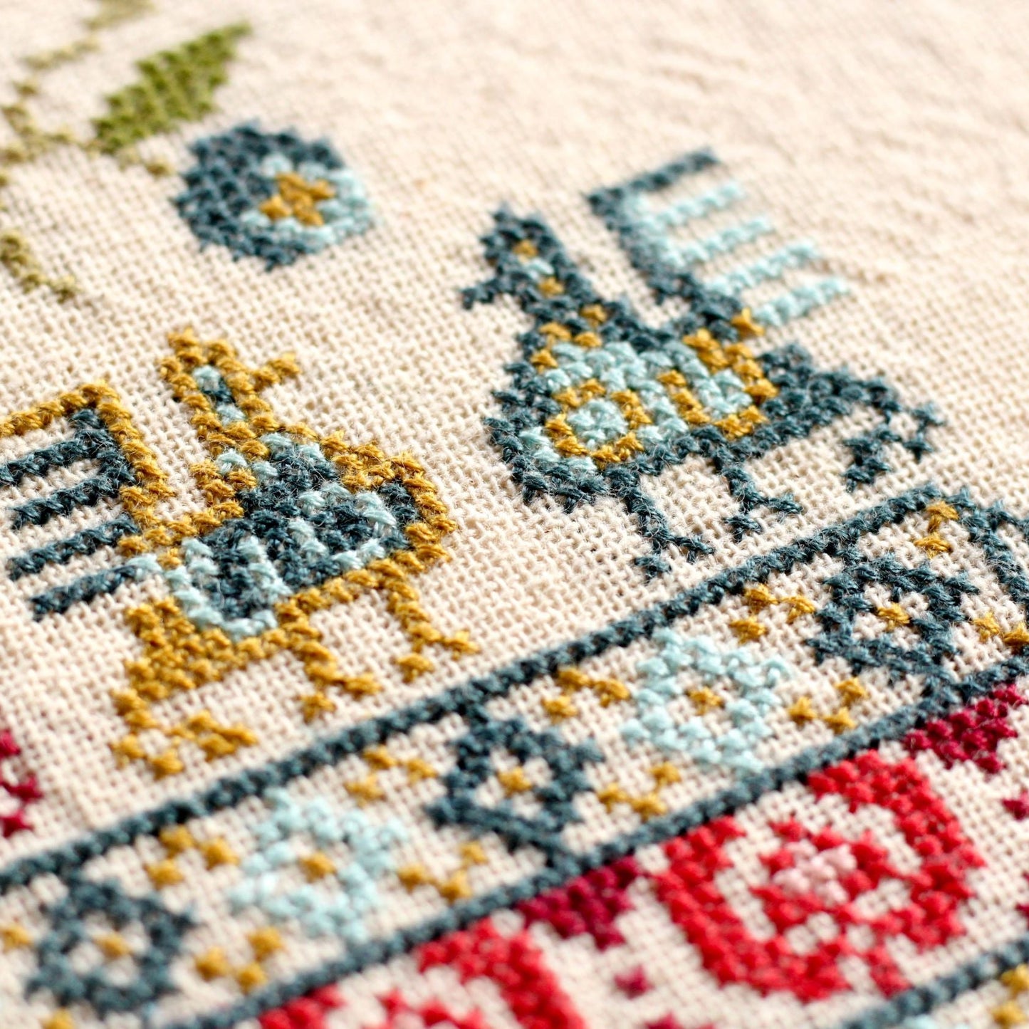 Close-up of a cross-stitched piece with colorful birds and flowers
