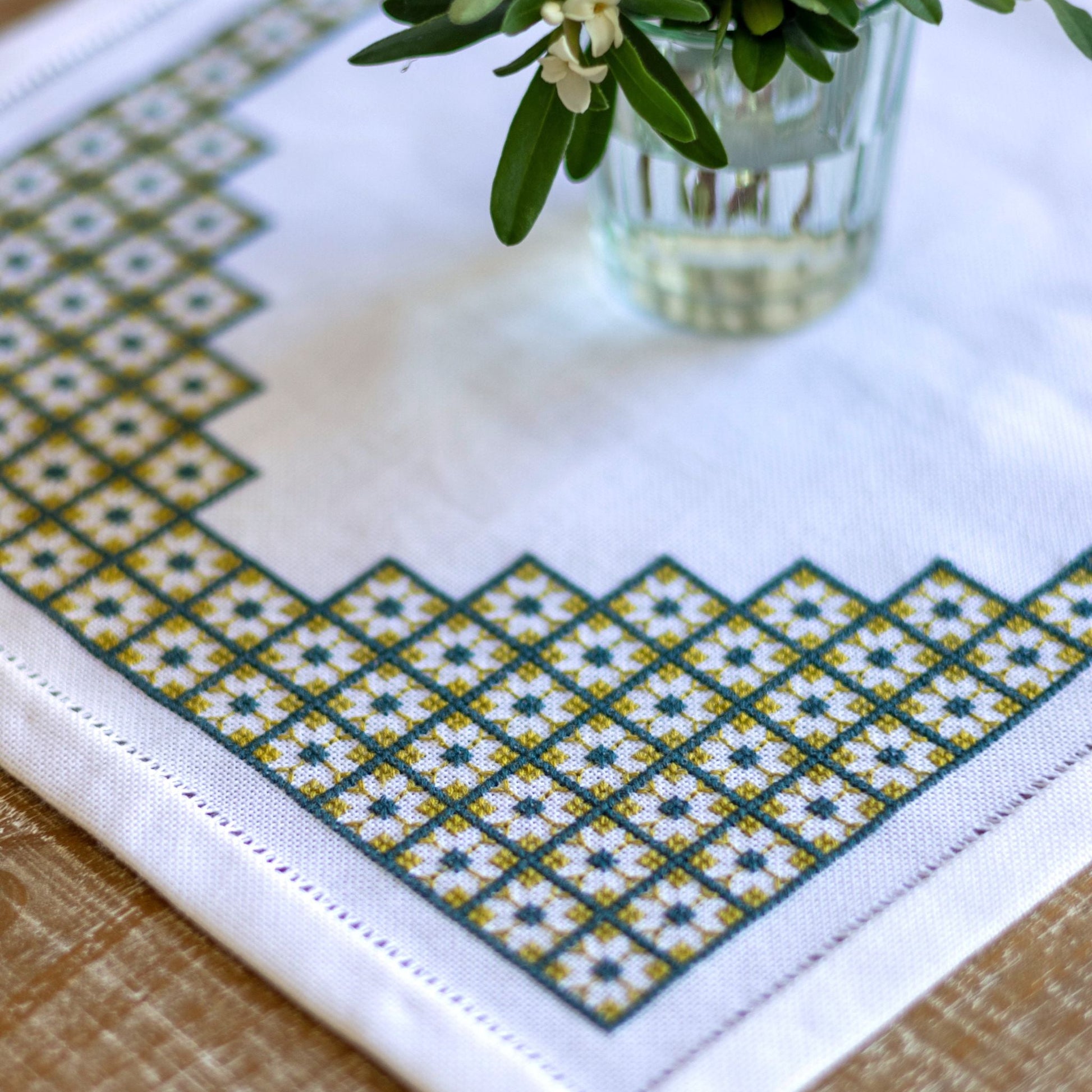 Embroidered tablecloth with geometric pattern on a wooden surface