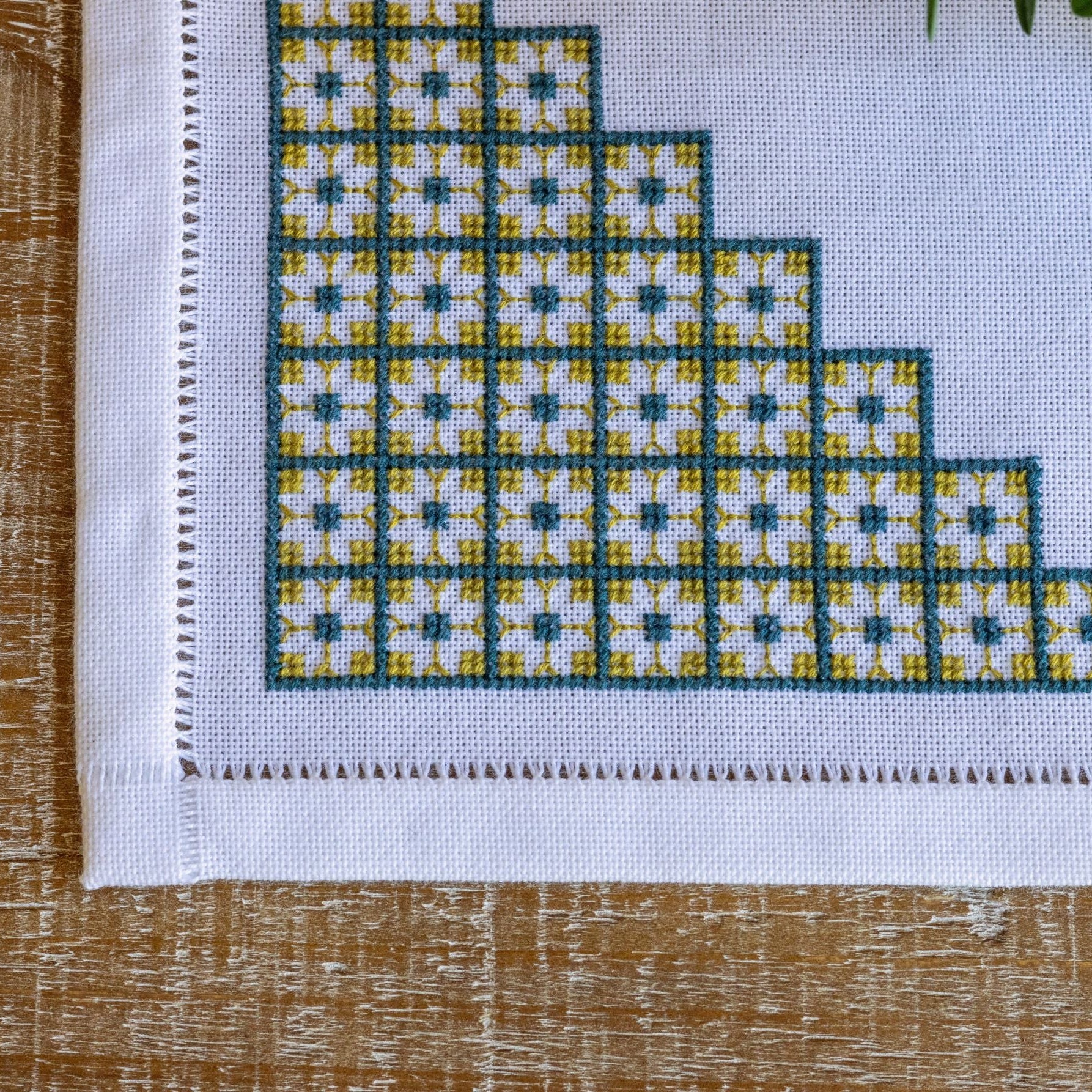 Cross-stitched pattern on fabric with a wooden surface underneath