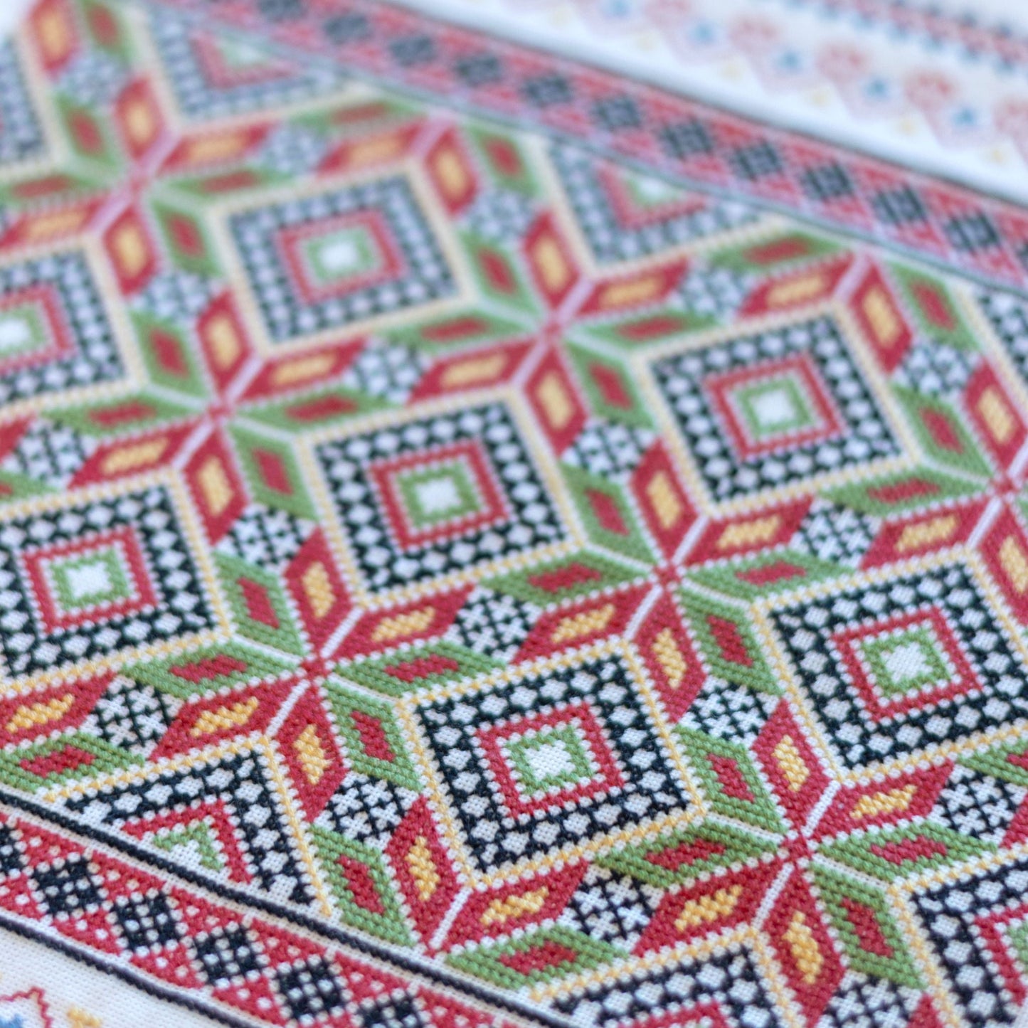 Close-up of a cross-stitched pattern with geometric design on fabric.