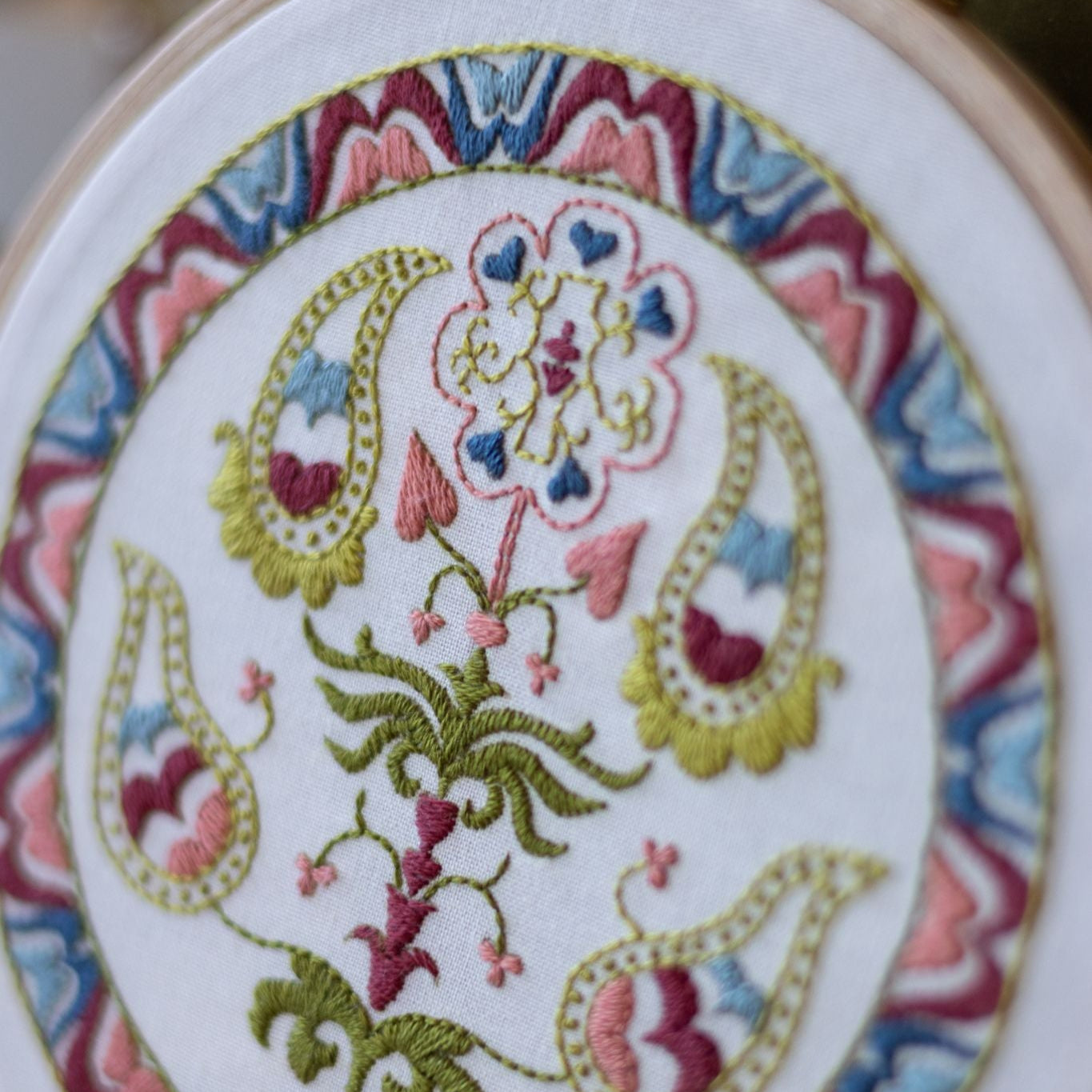 Embroidery hoop with floral and paisley pattern on white fabric