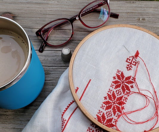 folk embroidery in hoop with mug of tea and eyeglasses