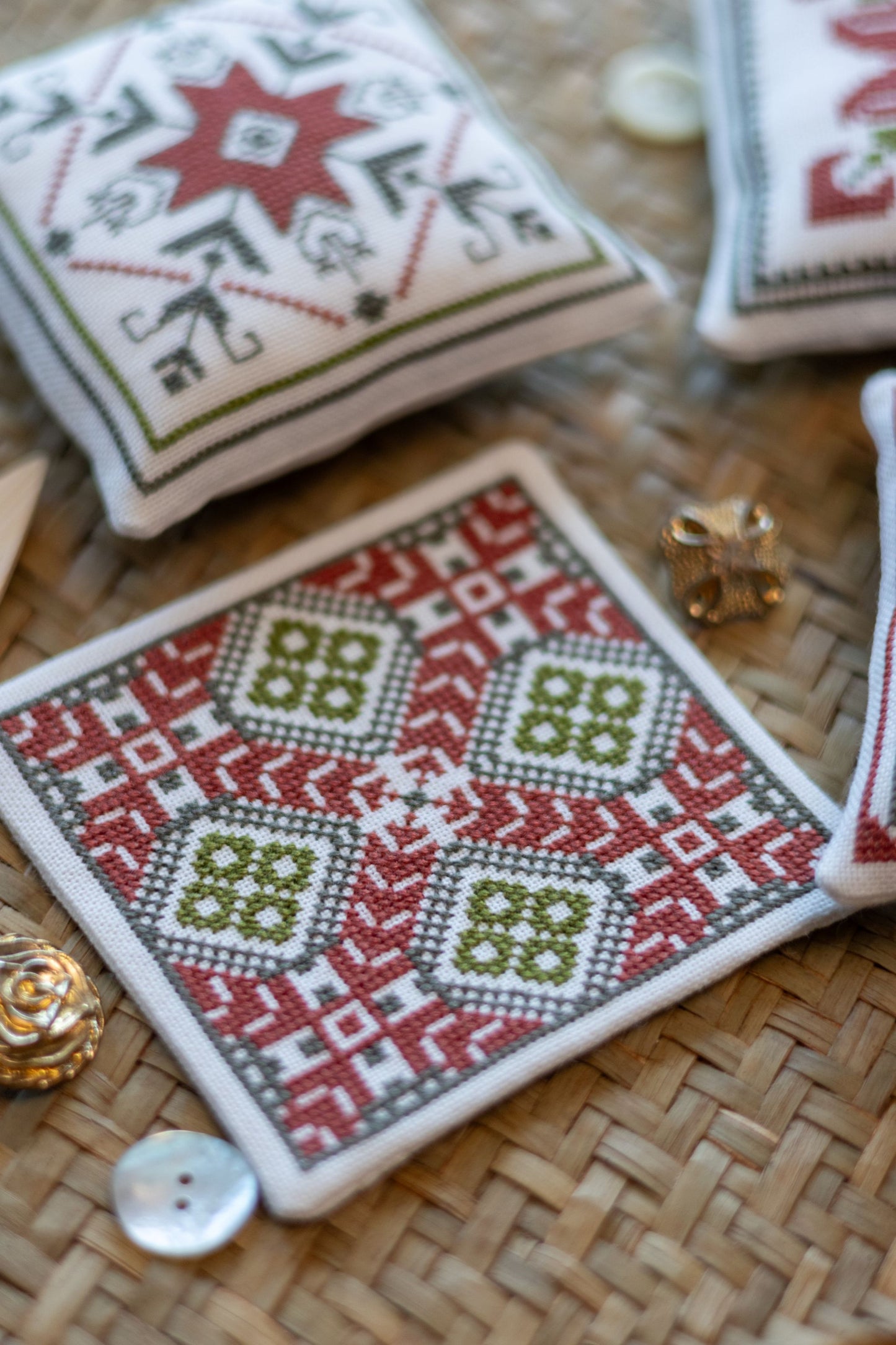 Cross-stitched coasters with geometric patterns on a woven surface