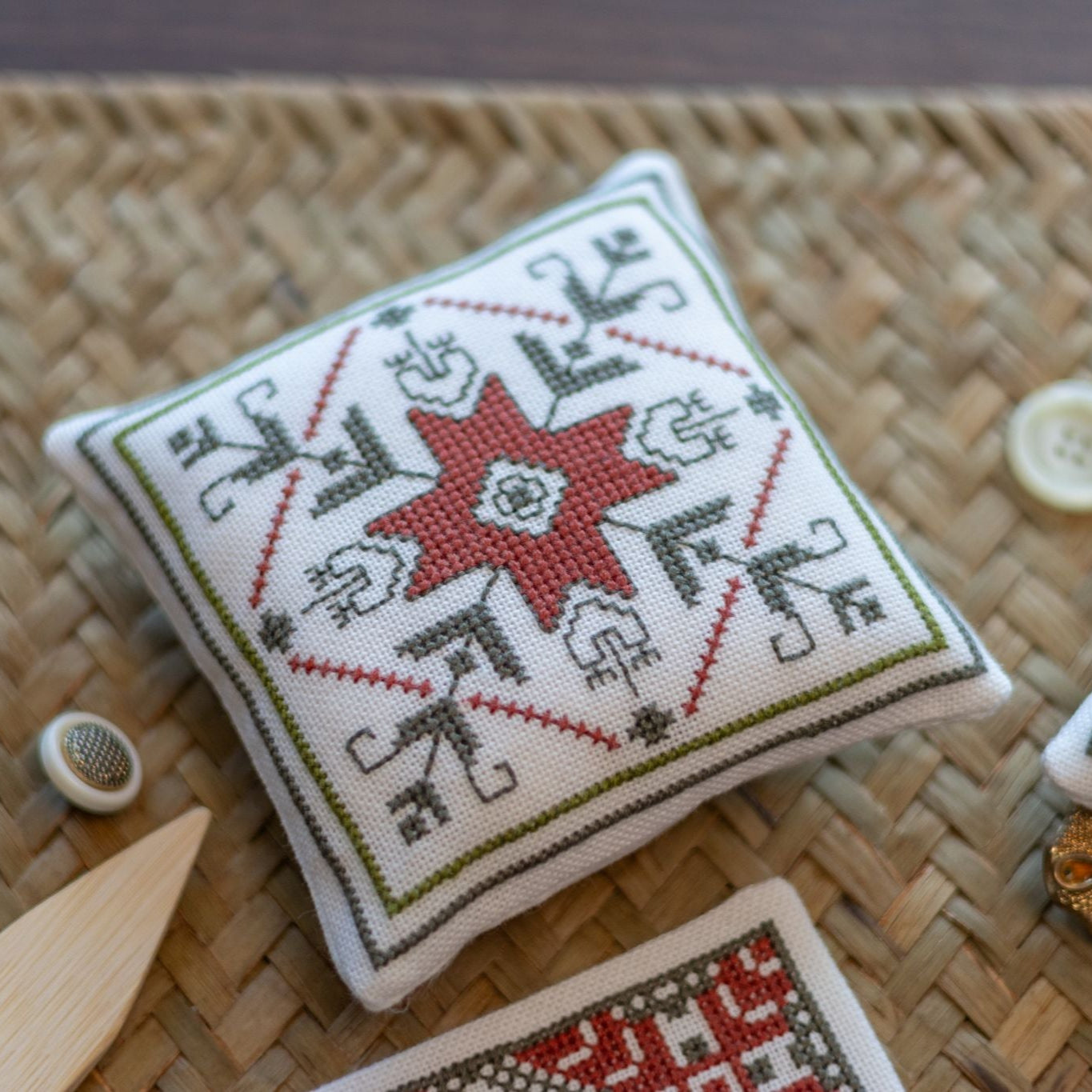Cross-stitched cushions with geometric patterns on a woven surface