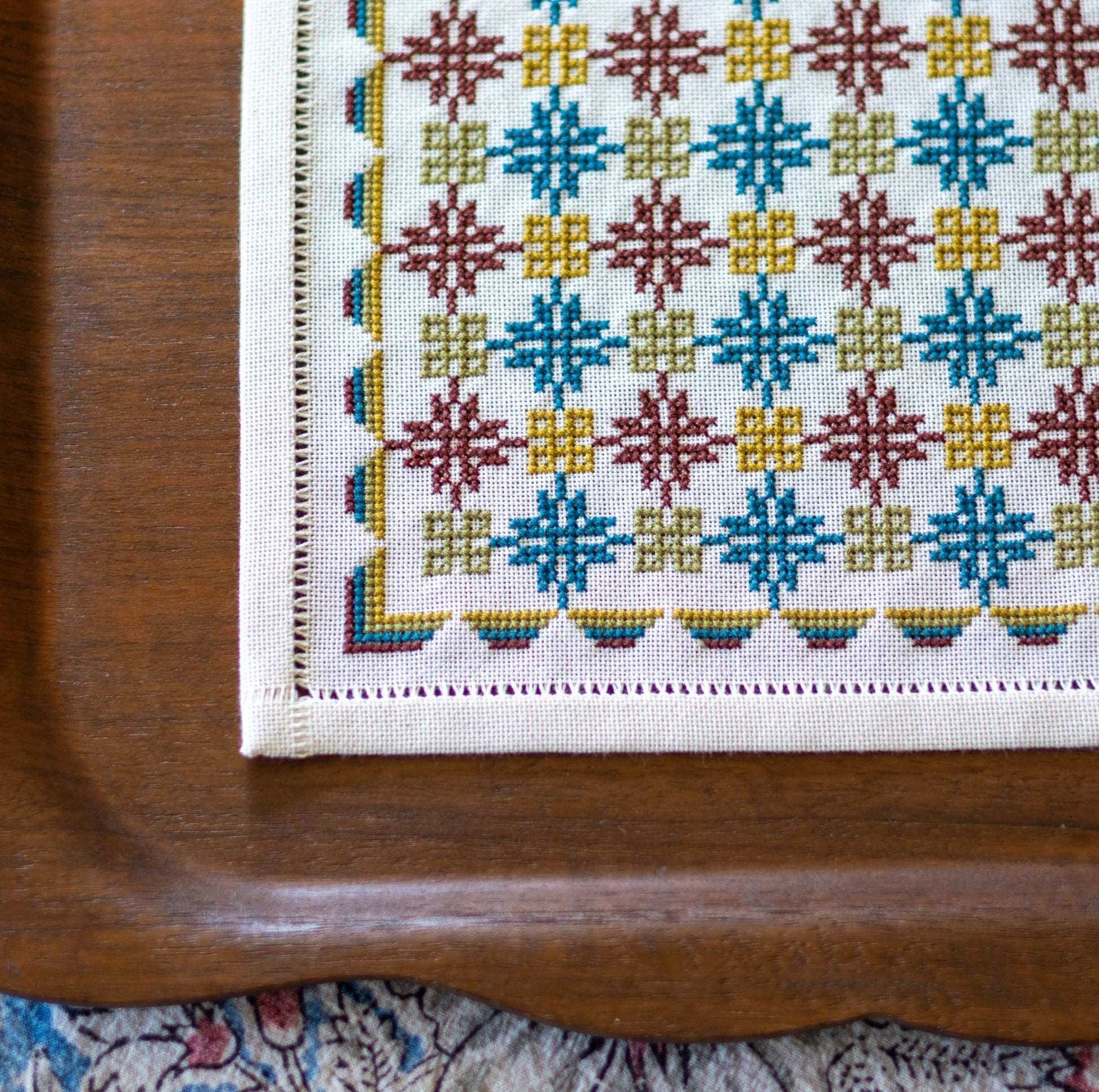 folk embroidery with repeating design in teal and burgundy