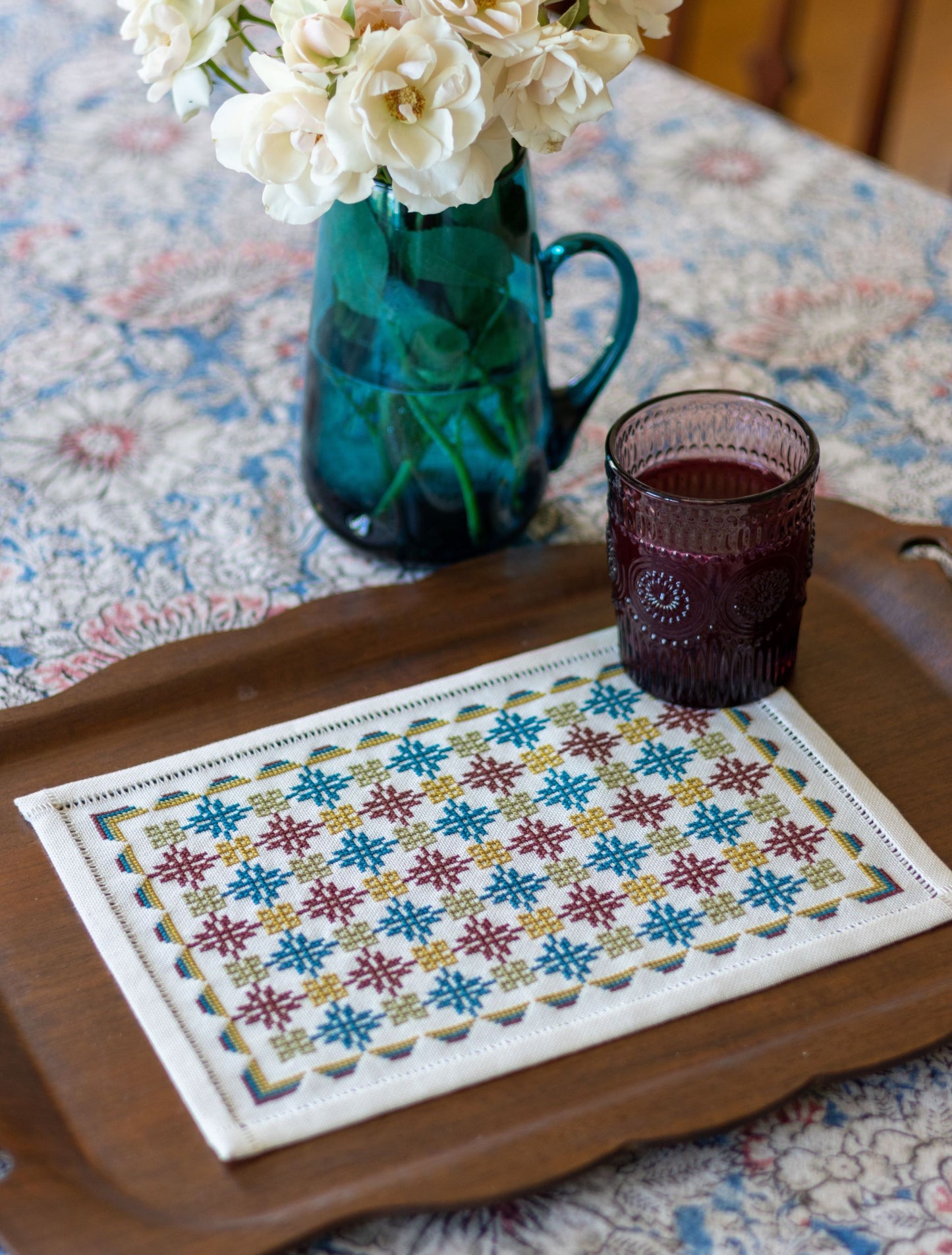 folk embroidery with repeating design in teal and burgundy