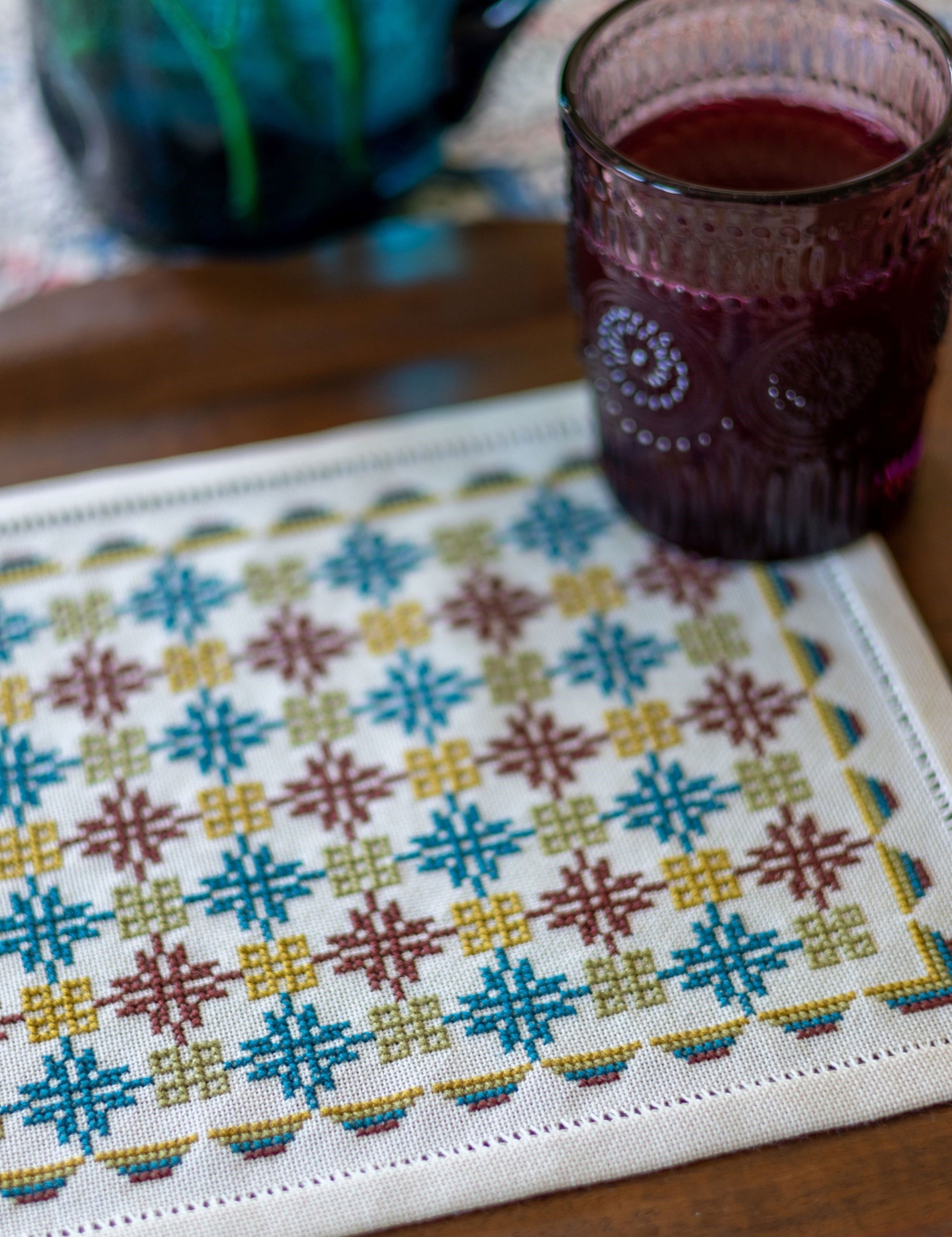 folk embroidery with repeating design in teal and burgundy