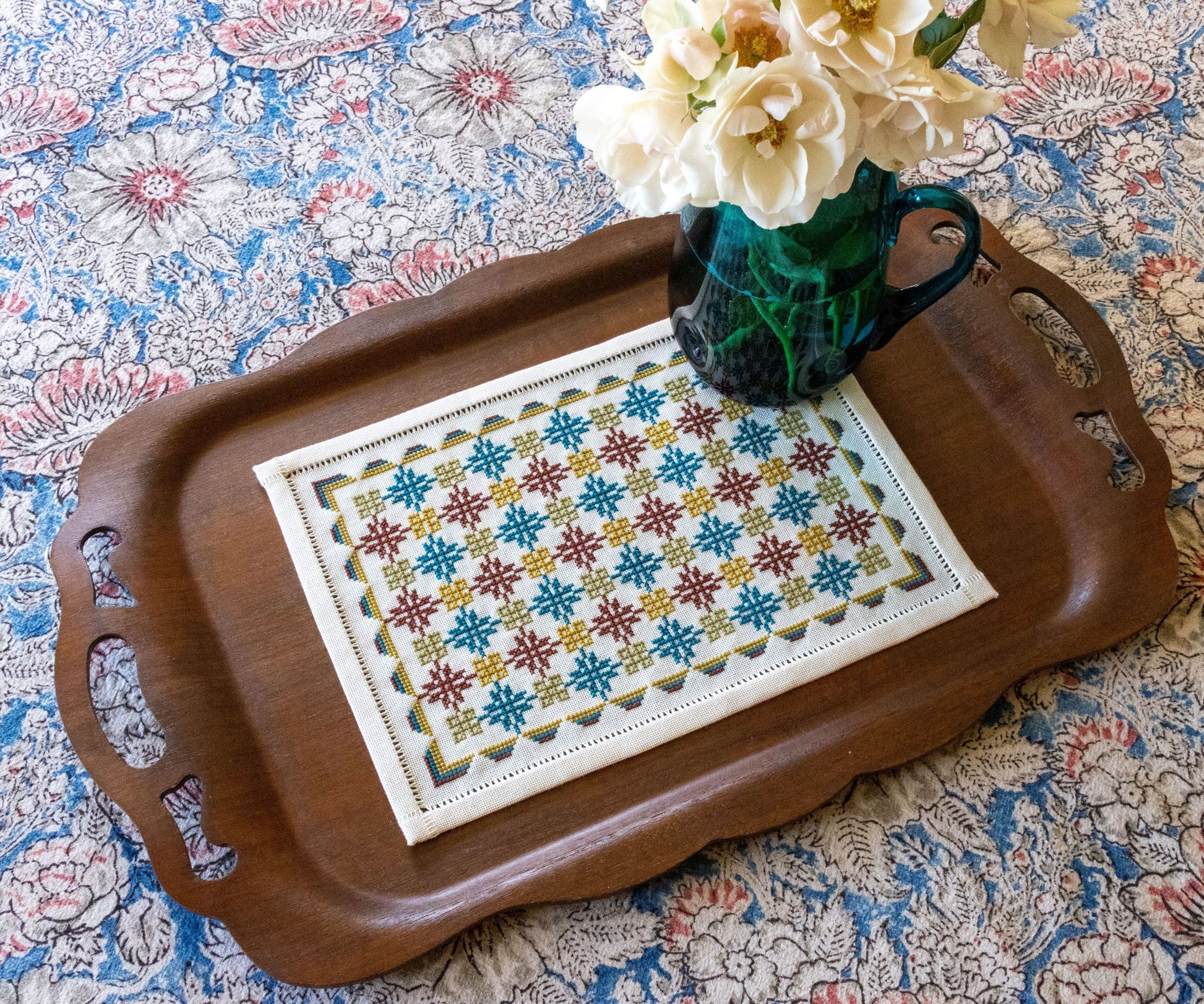 folk embroidery with repeating design in teal and burgundy