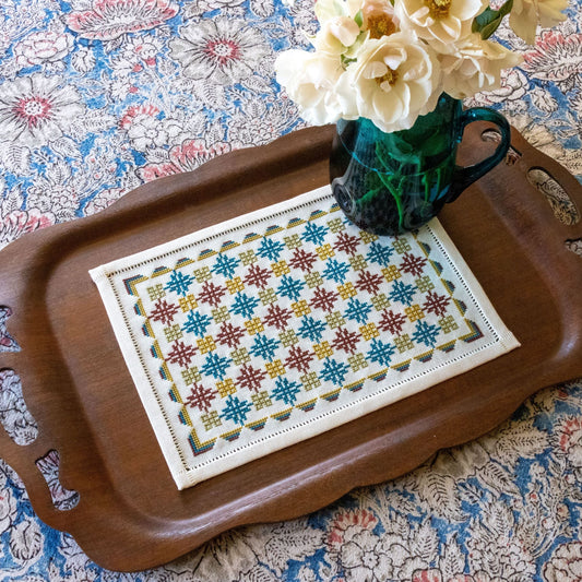 folk embroidery with repeating design in teal and burgundy