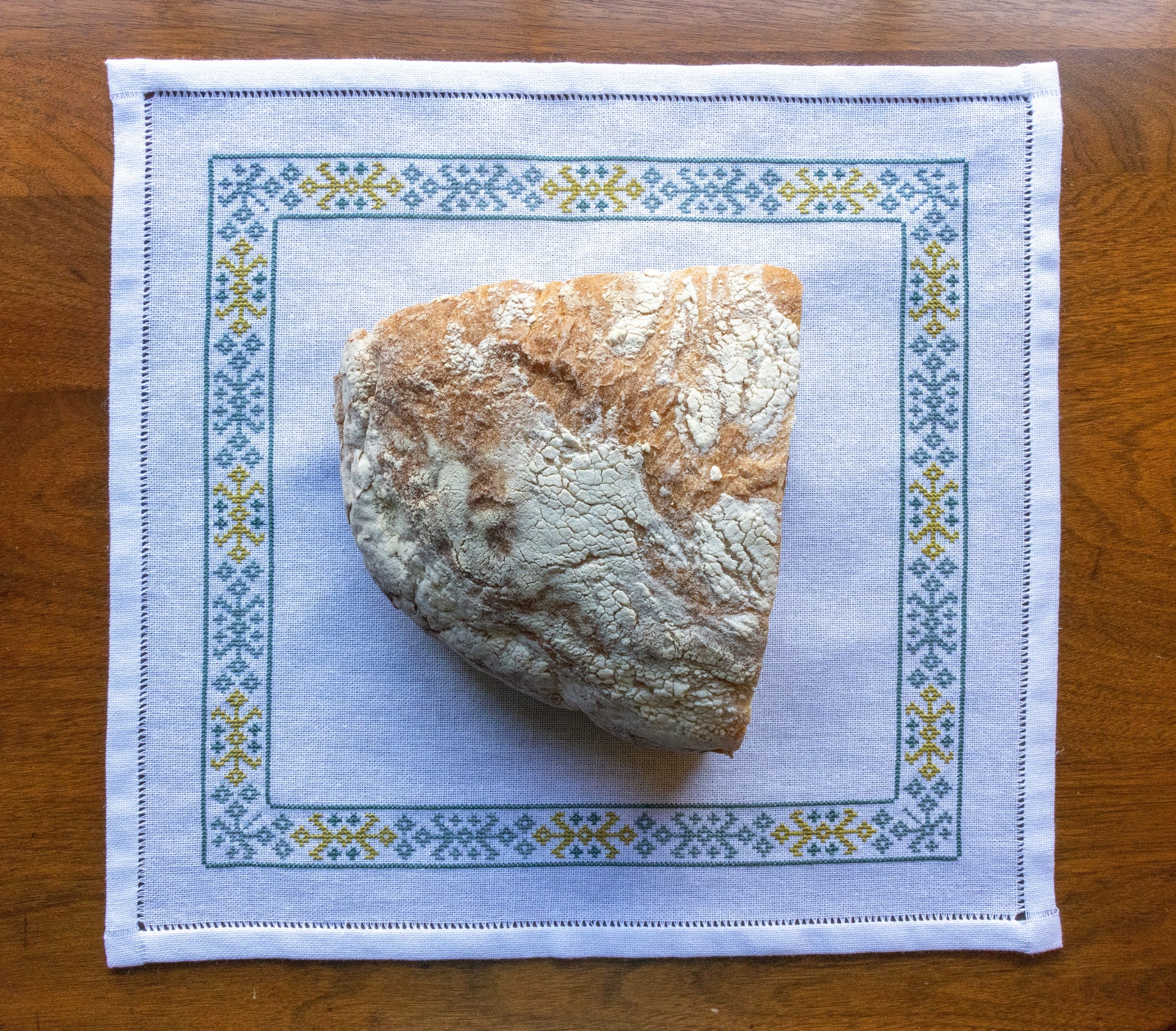 cloth with folk embroidery border in basket with bread