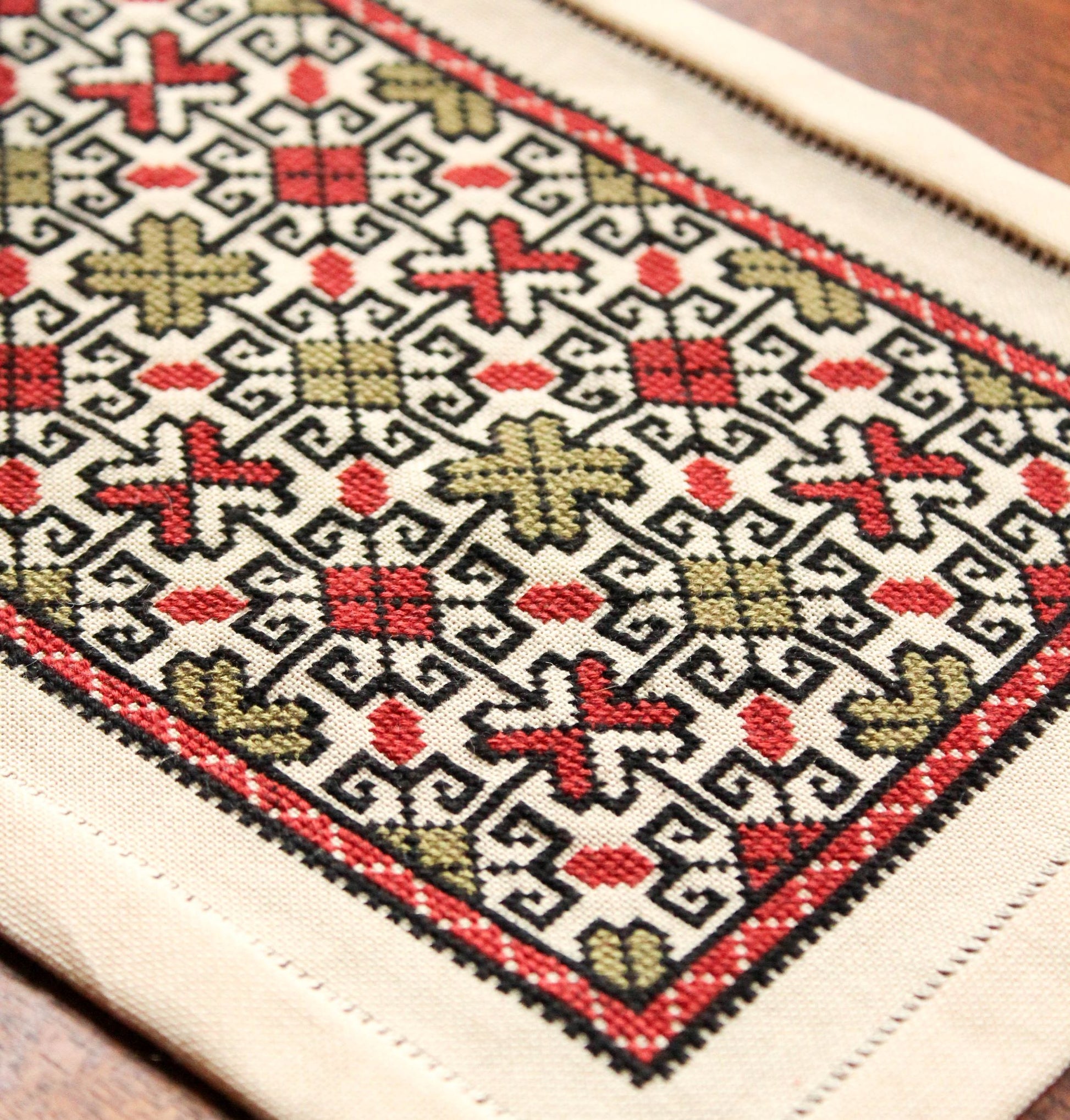 folk embroidery table mat with repeating design in red and black