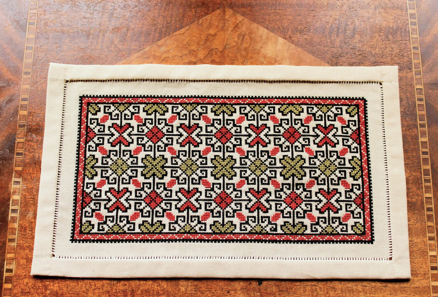 folk embroidery table mat with repeating design in red and black