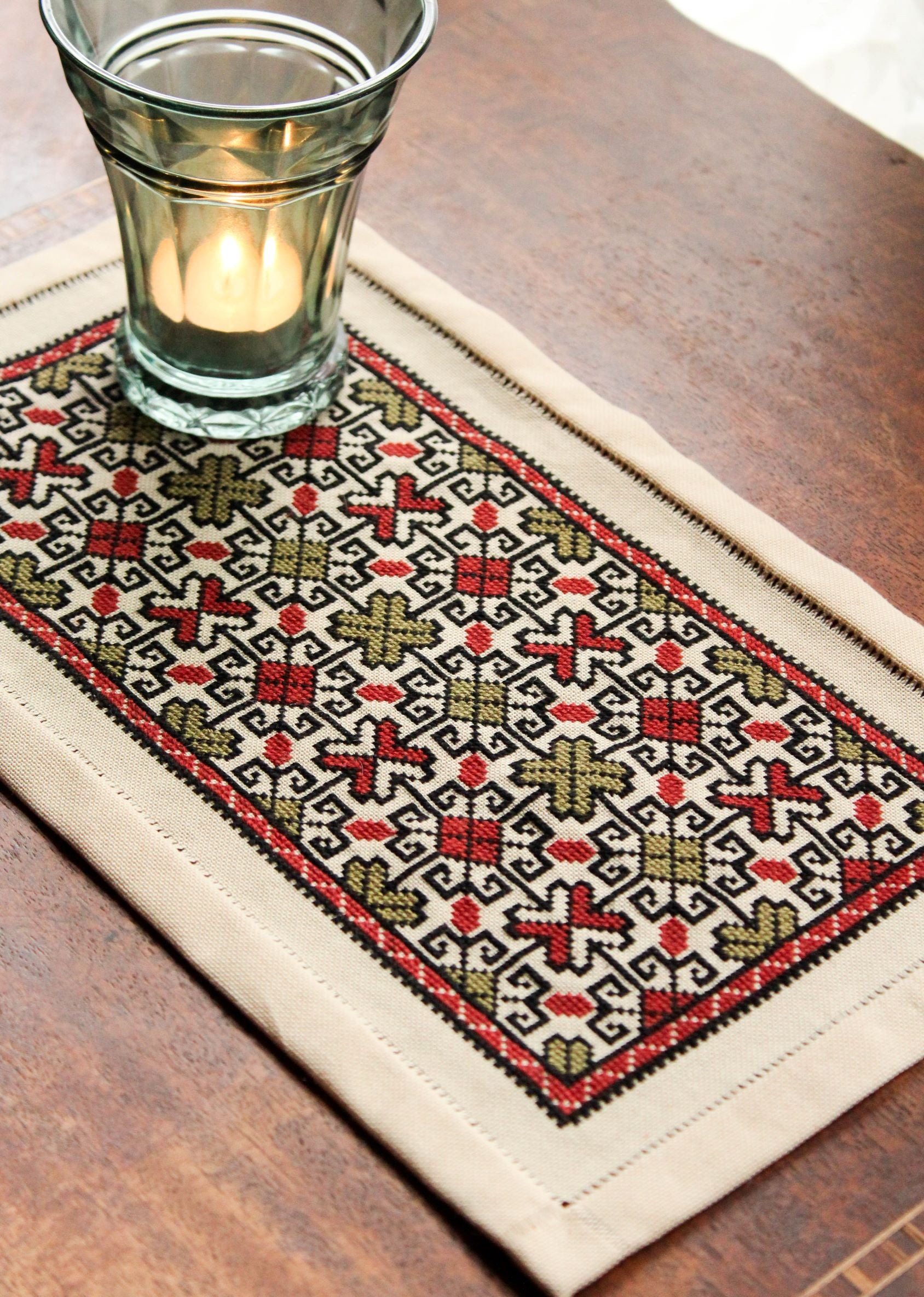 folk embroidery table mat with repeating design in red and black