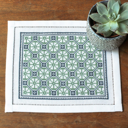 folk embroidery table mat with green and blue design and plant