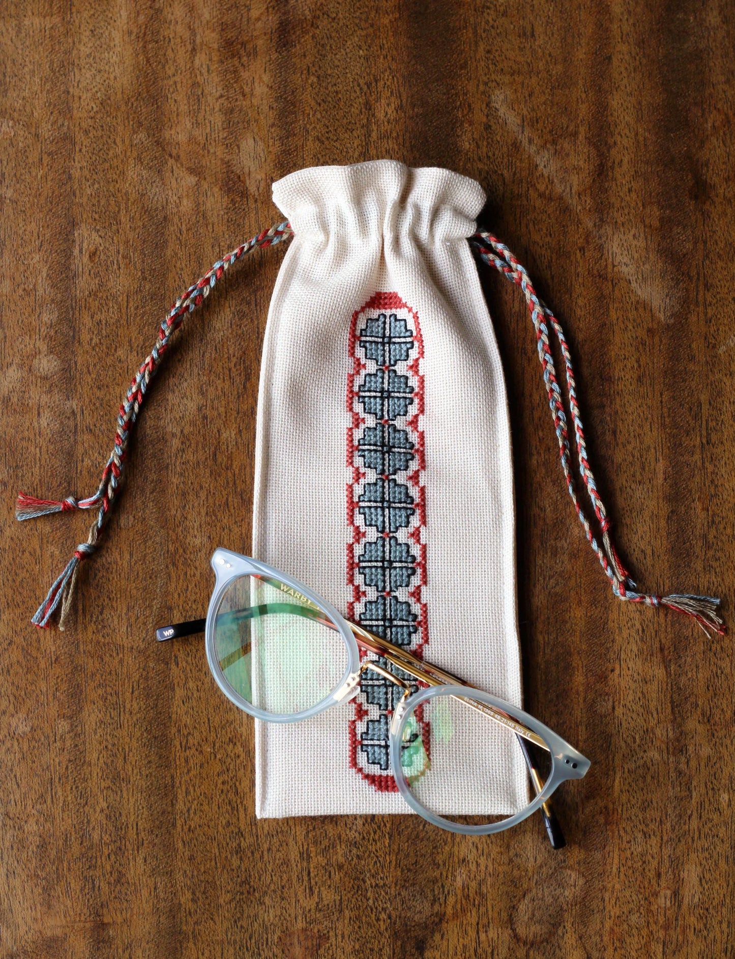 small drawstring bag with folk embroidery border and glasses