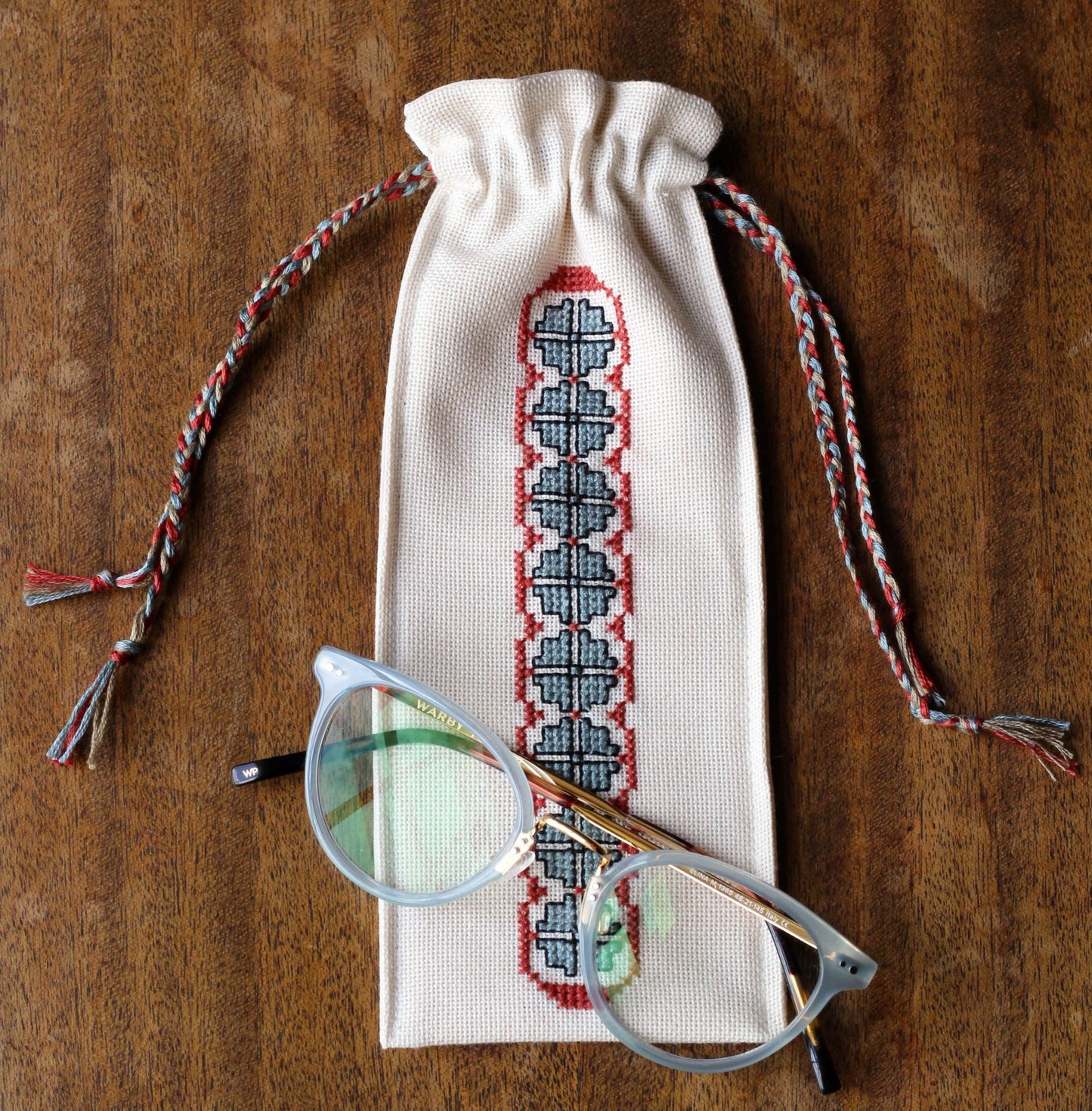 small drawstring bag with folk embroidery border and glasses