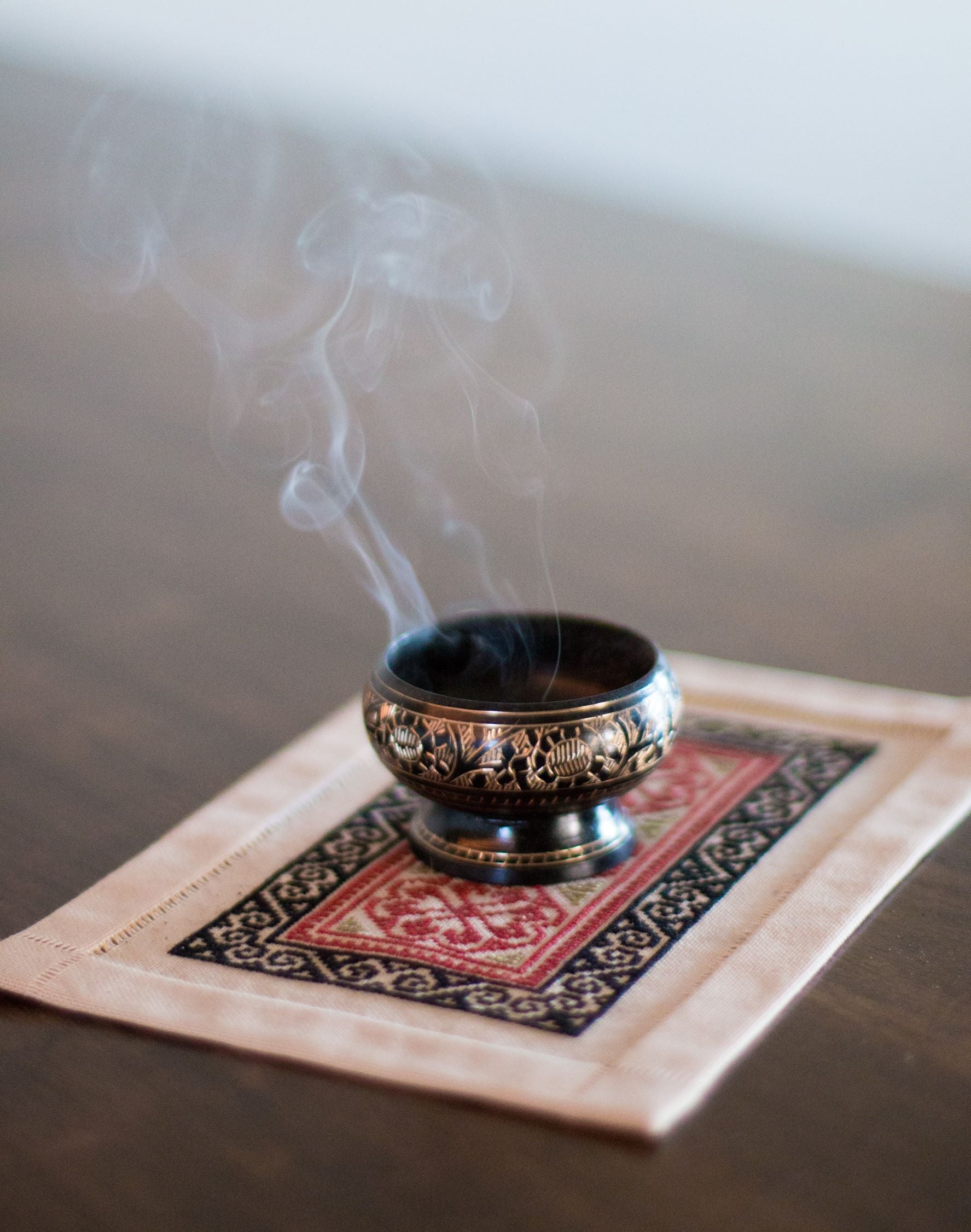 folk embroidery mat with bowl of incense