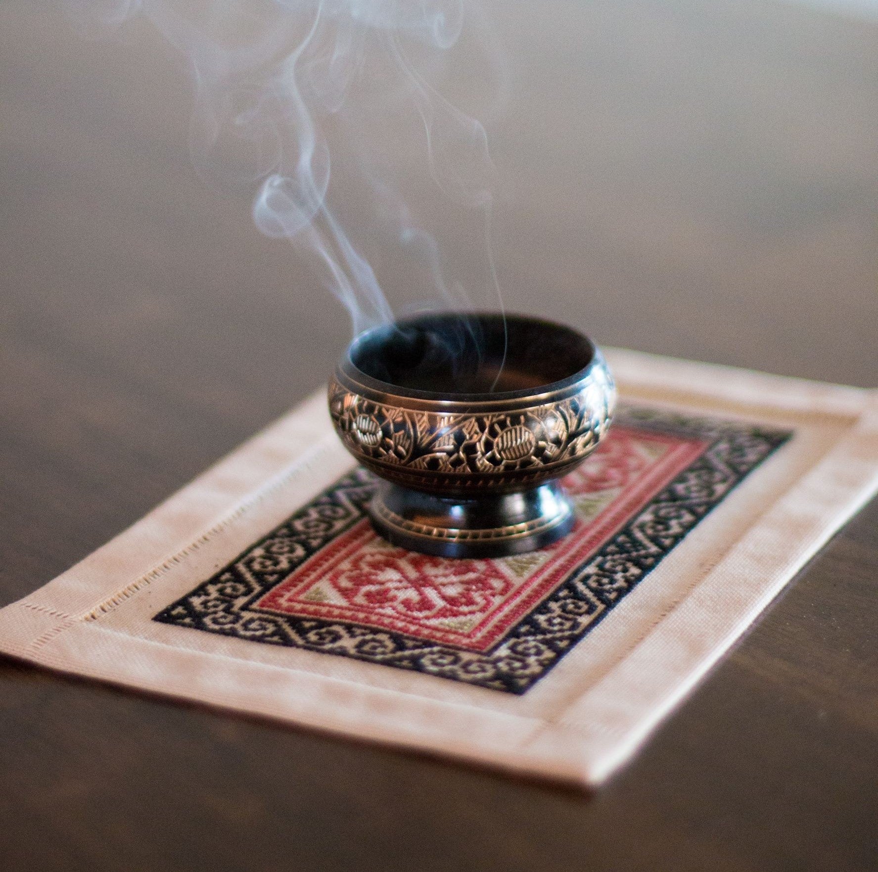 folk embroidery mat with bowl of incense