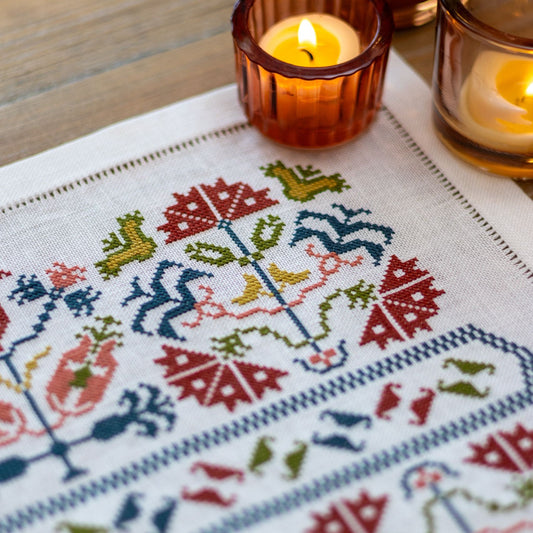 Greek cross stitch folk embroidery on linen with flower design closeup with candles