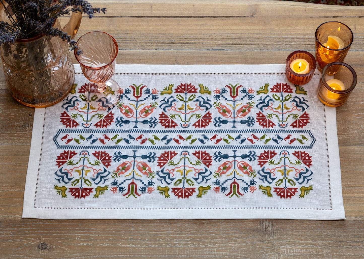 Greek cross stitch folk embroidery on linen with flower design closeup with candles and flowers