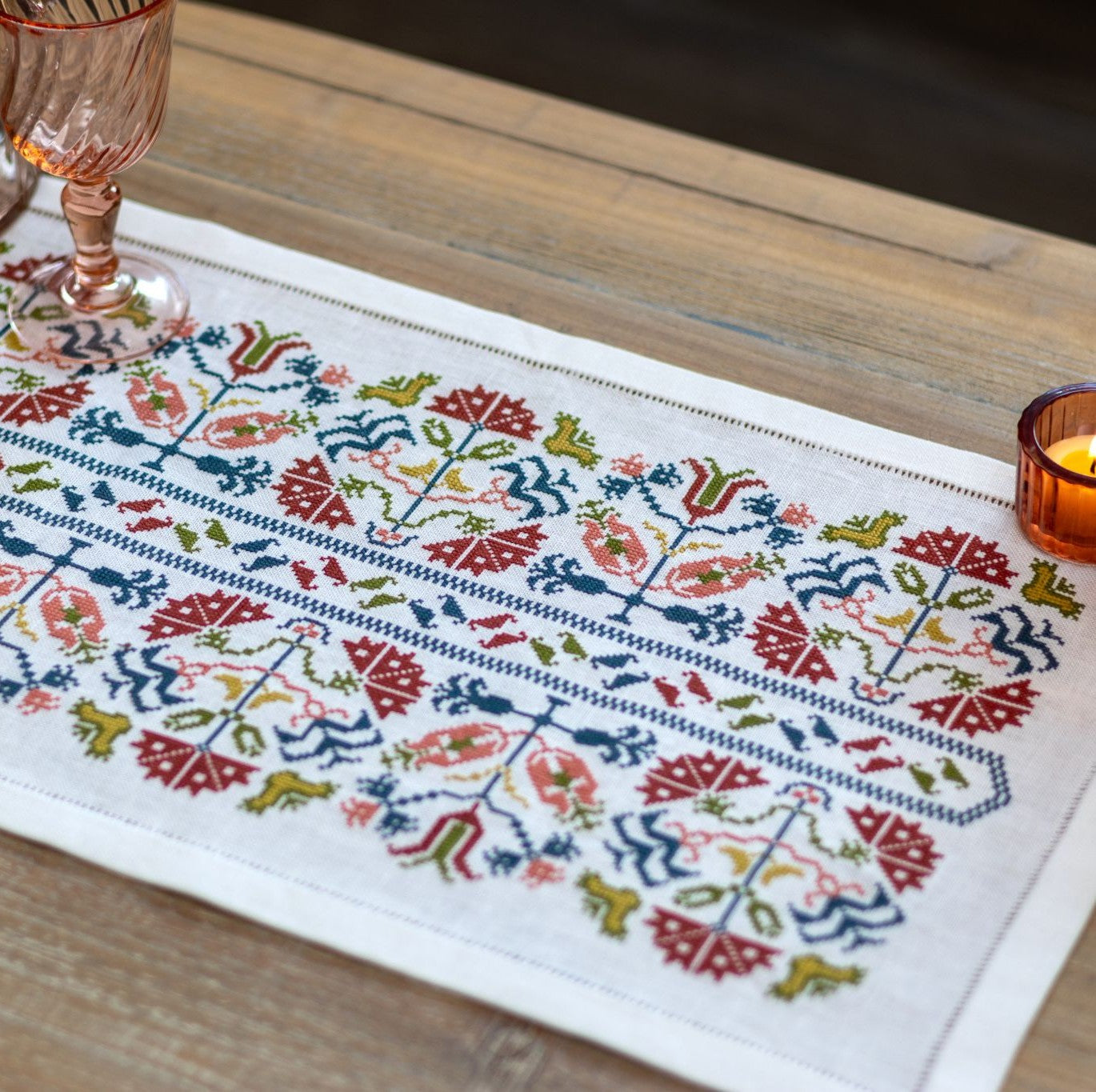Greek cross stitch folk embroidery on linen with flower design closeup with candles