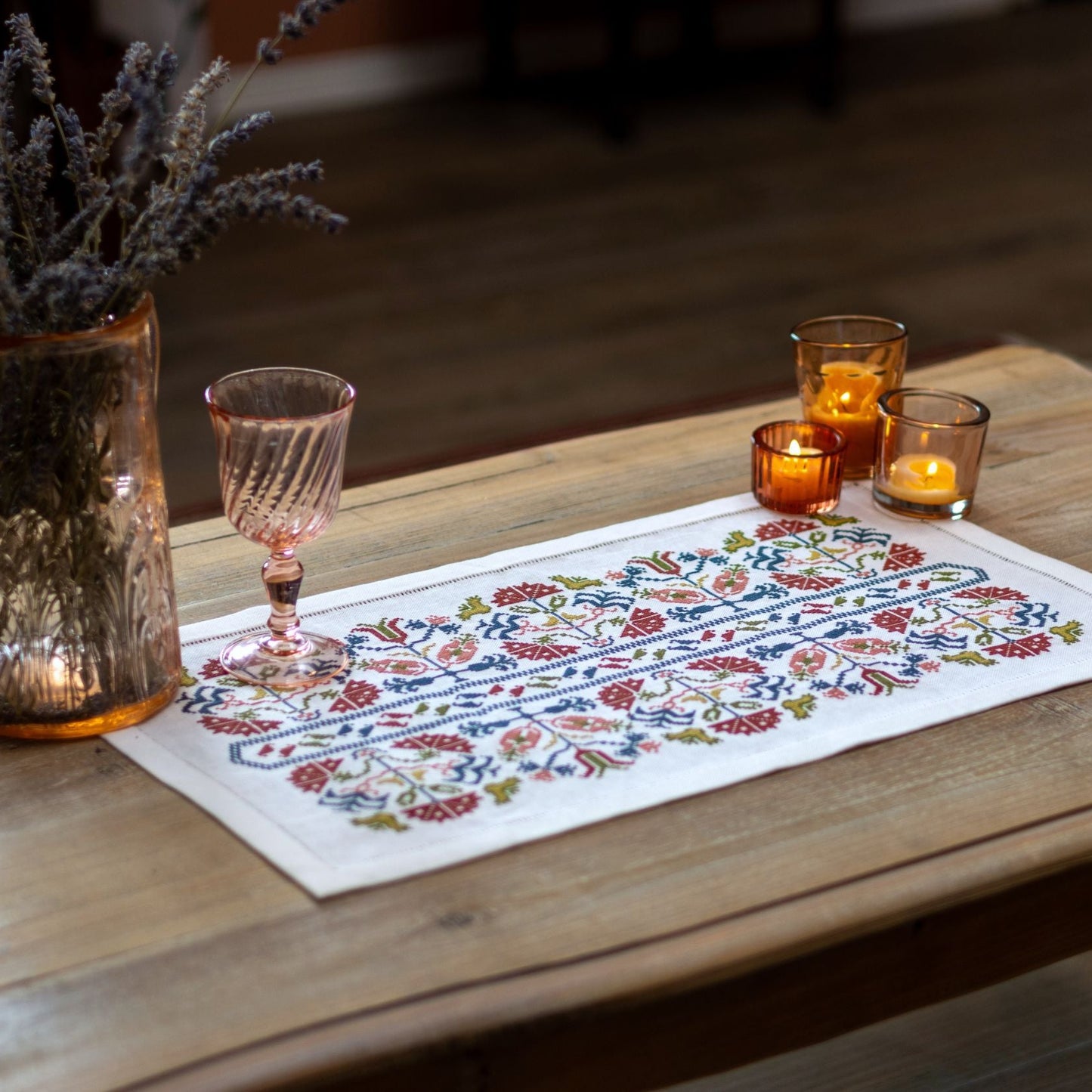 Greek cross stitch folk embroidery on linen with flower design closeup with candles on wooden table