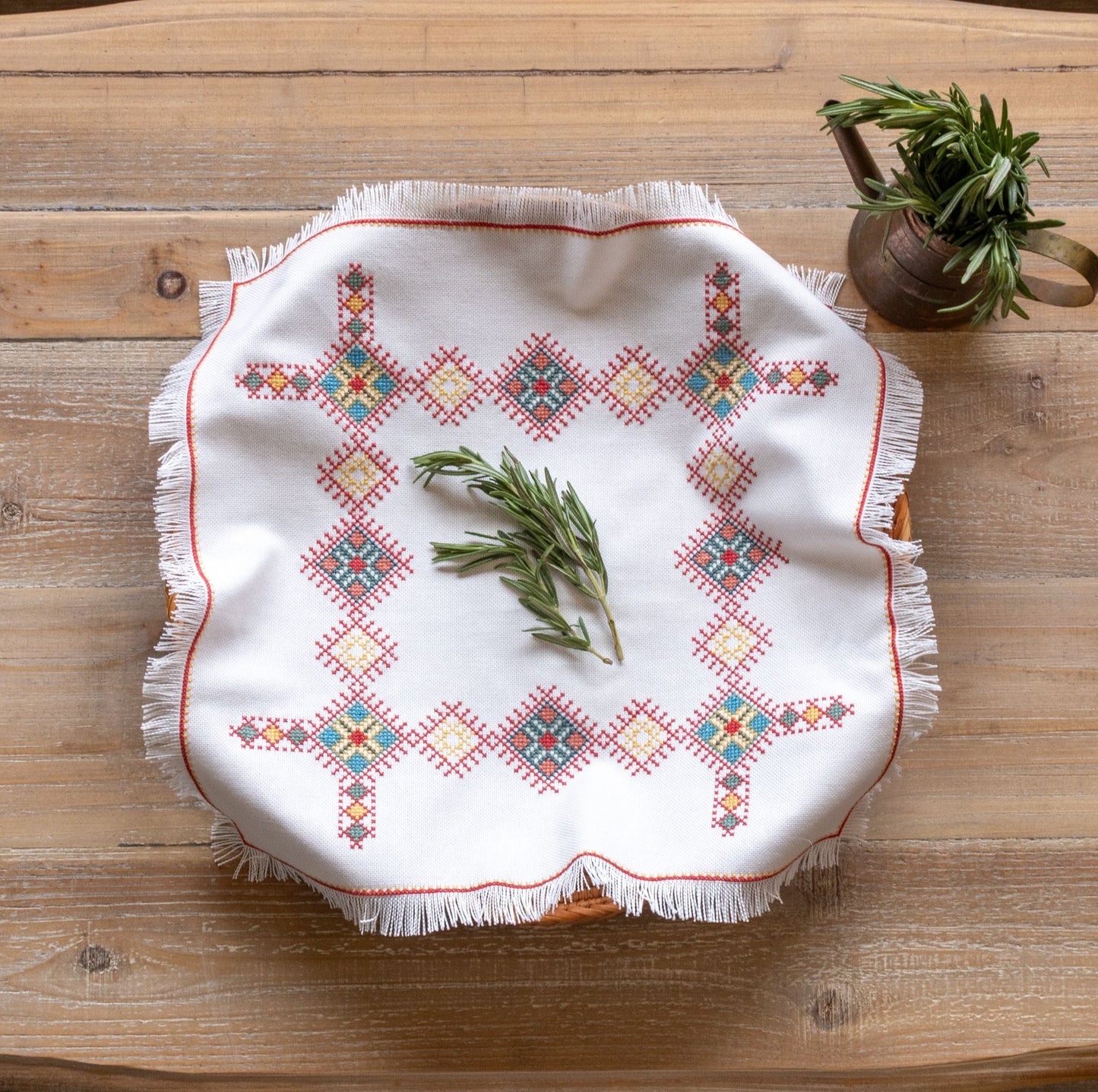 cross stitch folk embroidery Greek design basket cloth with herbs on table