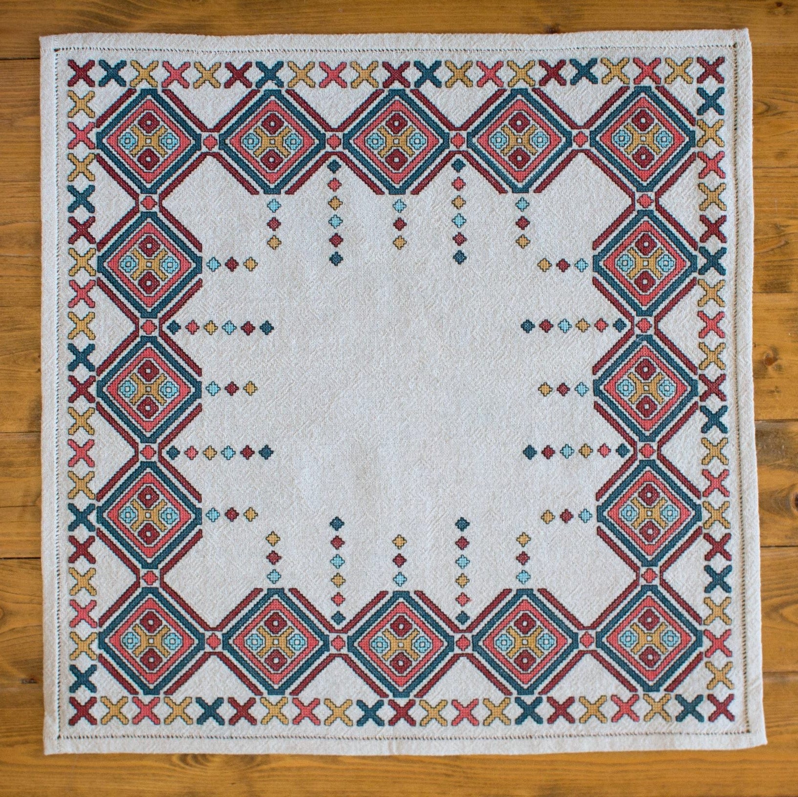 Embroidered quilt with geometric pattern on a wooden surface