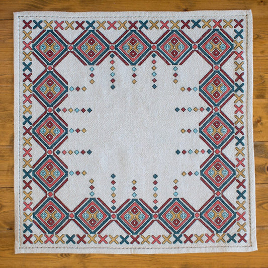 Embroidered quilt with geometric pattern on a wooden surface