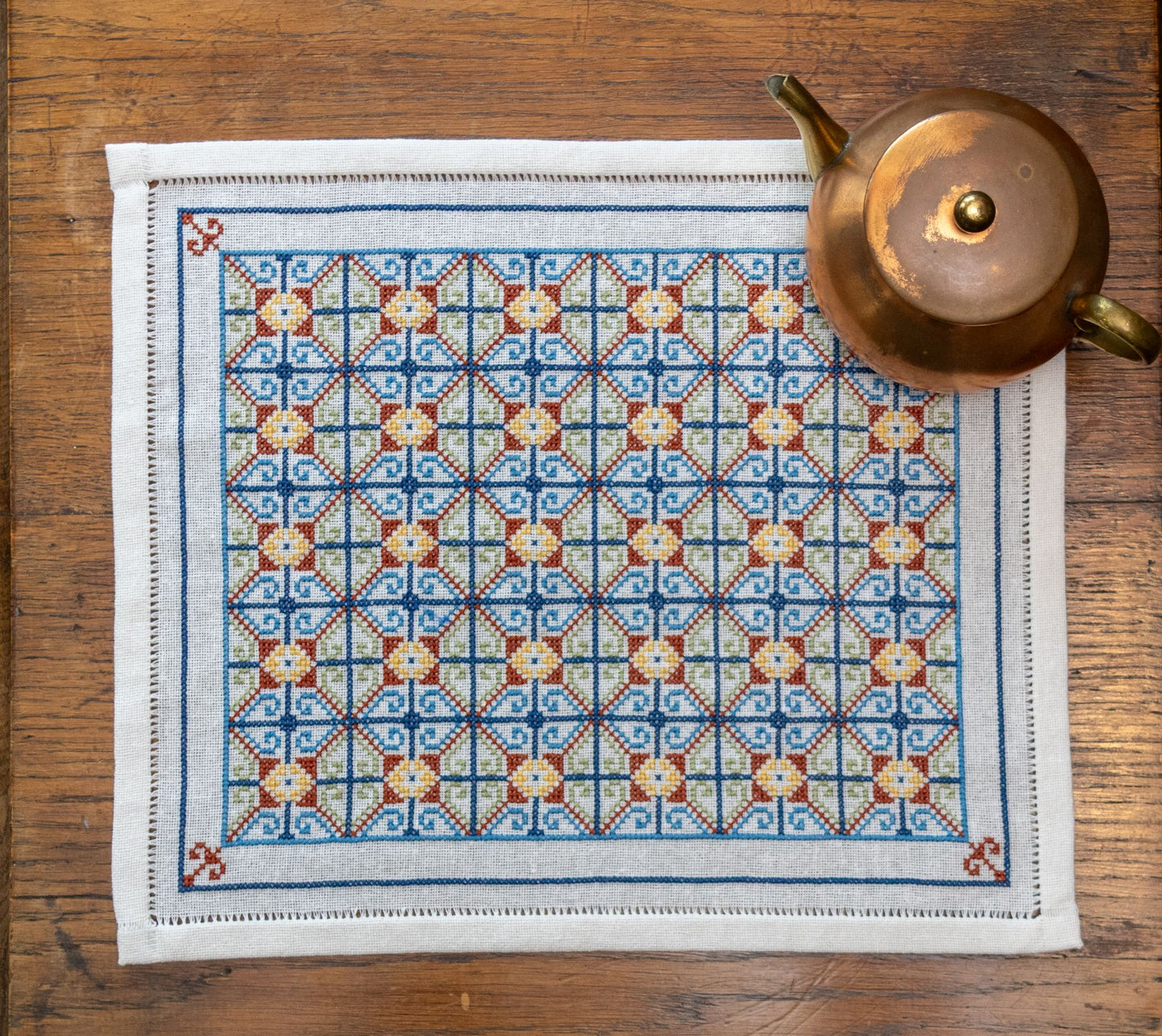 cross stitch folk embroidery repeating pattern closeup on table with teapot