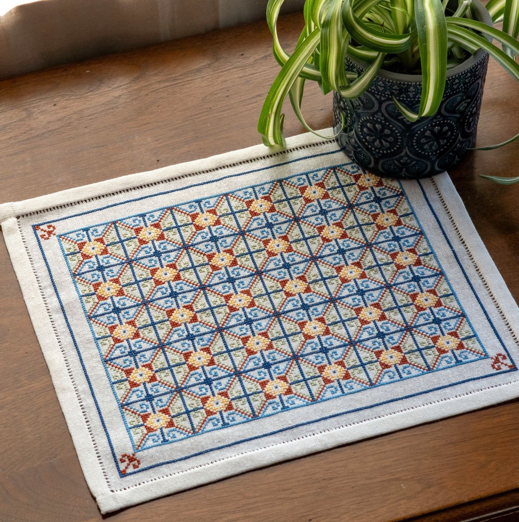 cross stitch folk embroidery repeating pattern closeup on table with plant