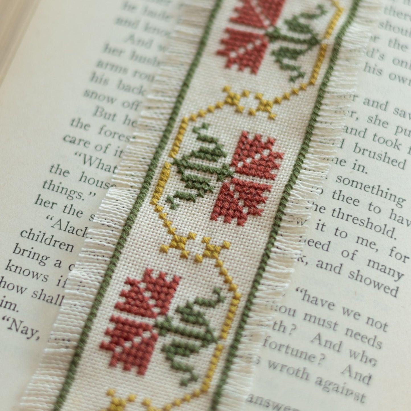 Cross-stitched bookmark with floral design on an open book