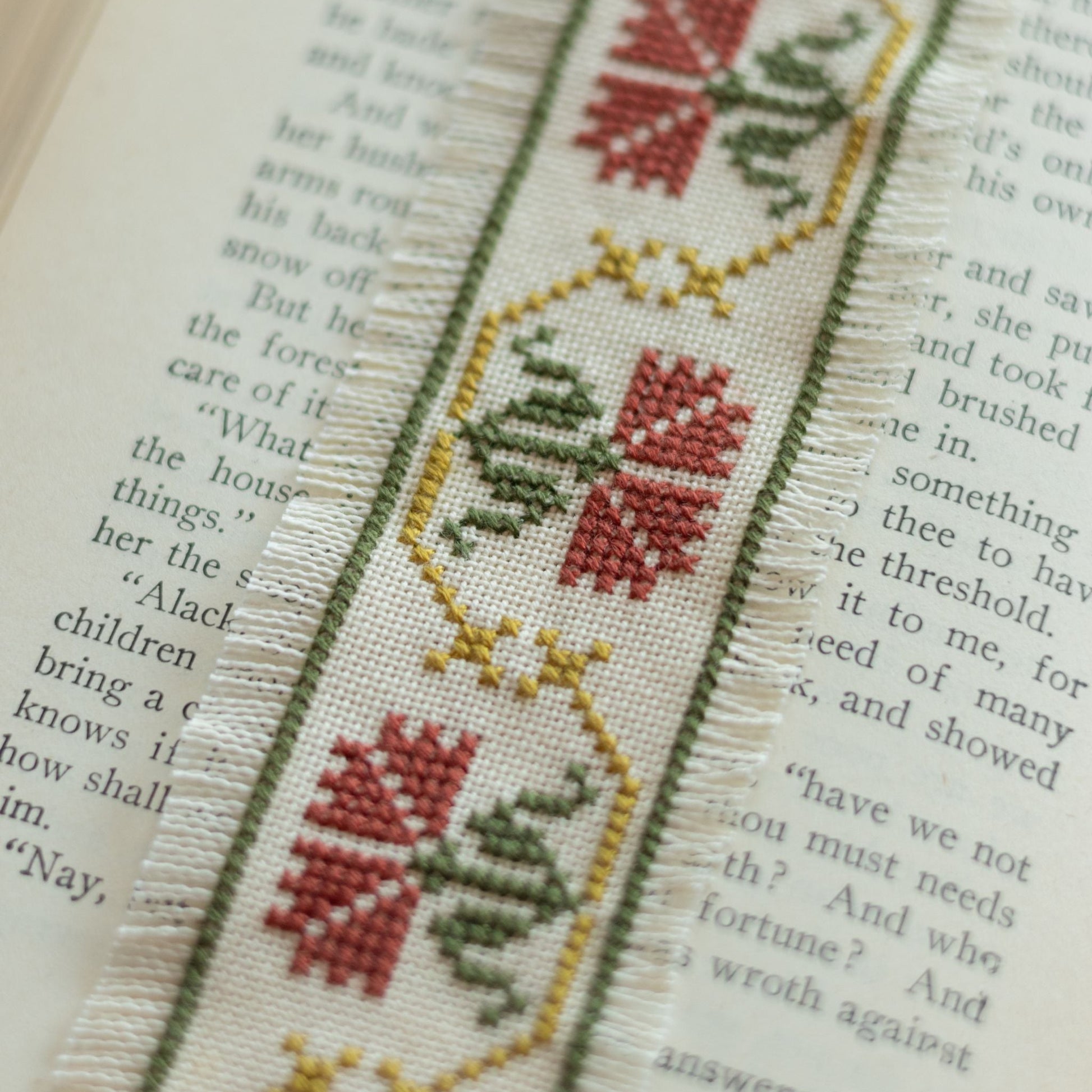 Cross-stitched bookmark with floral design on an open book