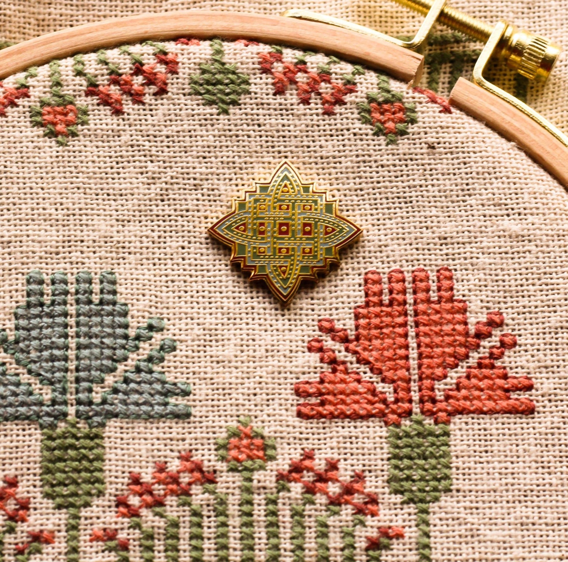 embroidery needleminder with knot design in red blue and green shown on folk embroidery