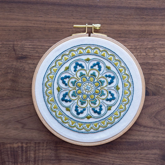 Embroidery hoop with a colorful mandala design on a wooden surface