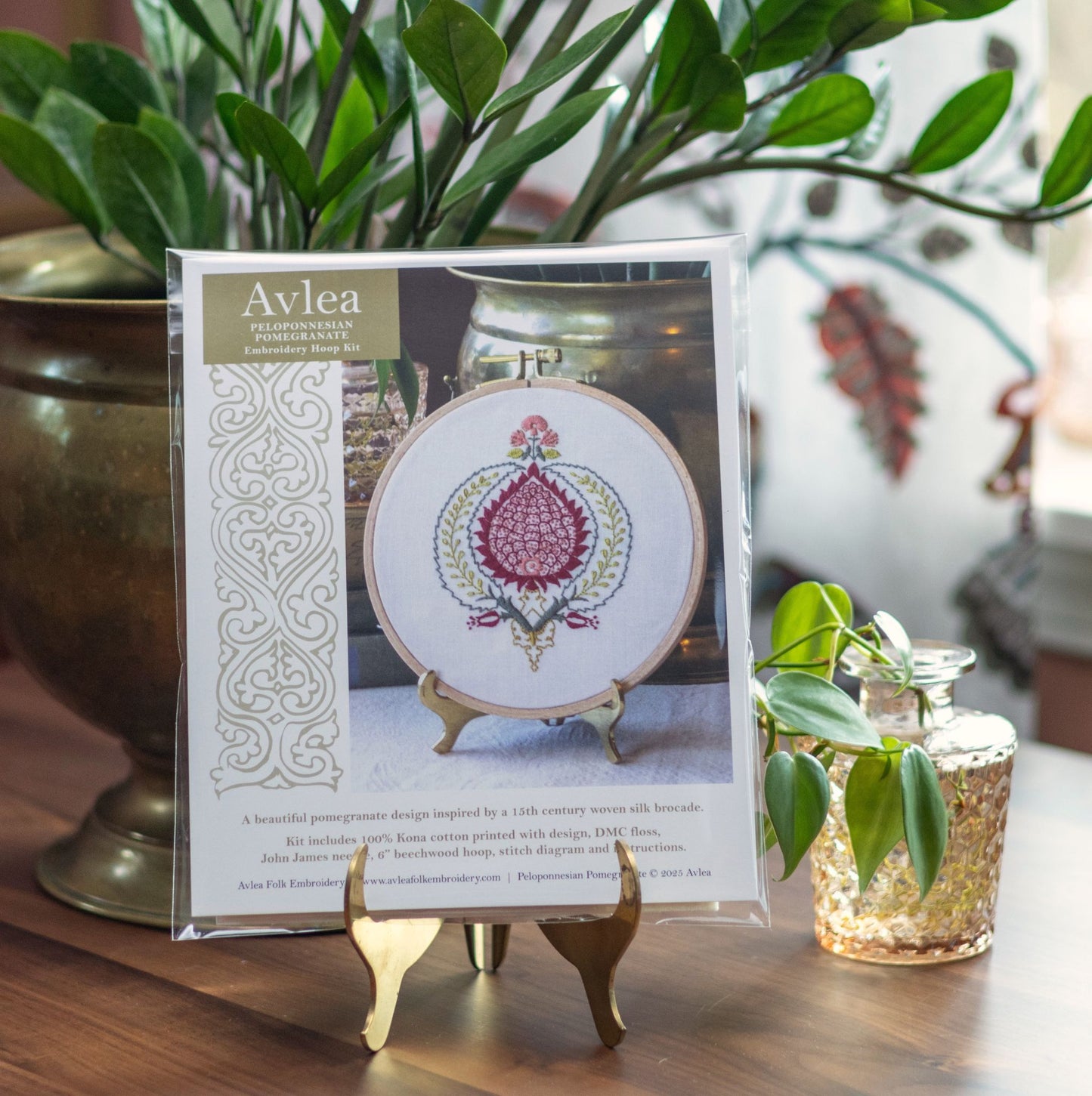 Avlea embroidery hoop kit packaging on a wooden surface with plants in the background