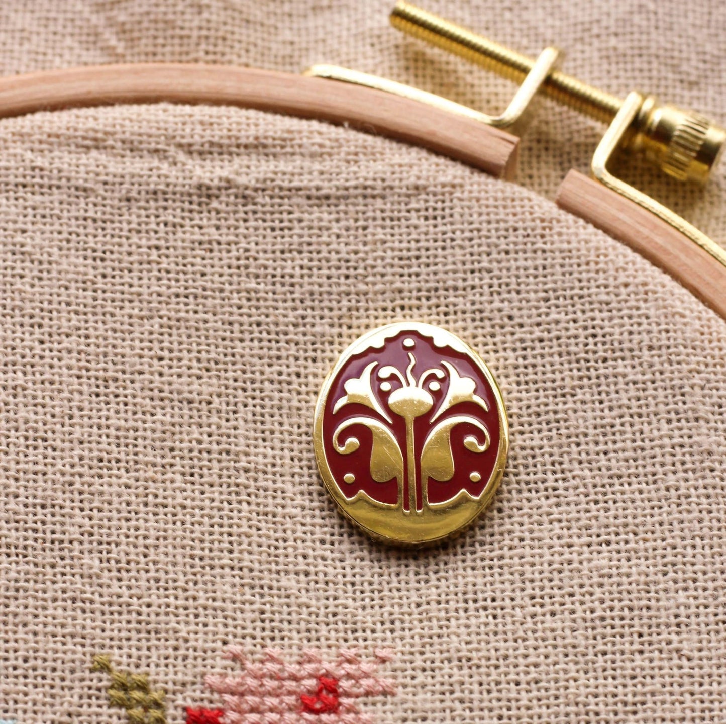 embroidery needleminder with stylized flower motif shown on folk embroidery in hoop