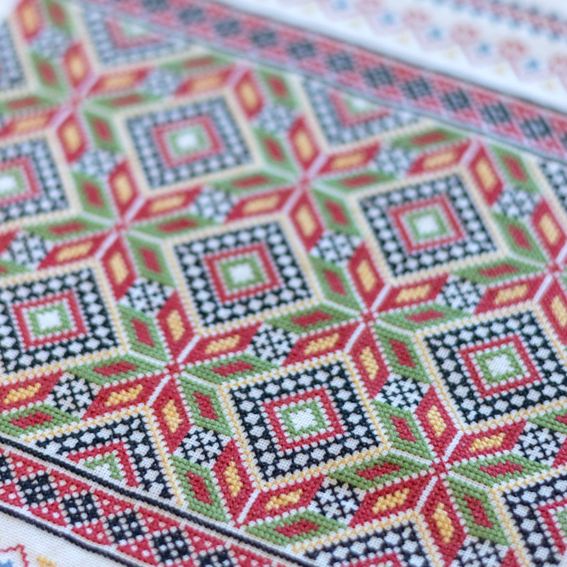 Close-up of a cross-stitched pattern with geometric design on fabric.