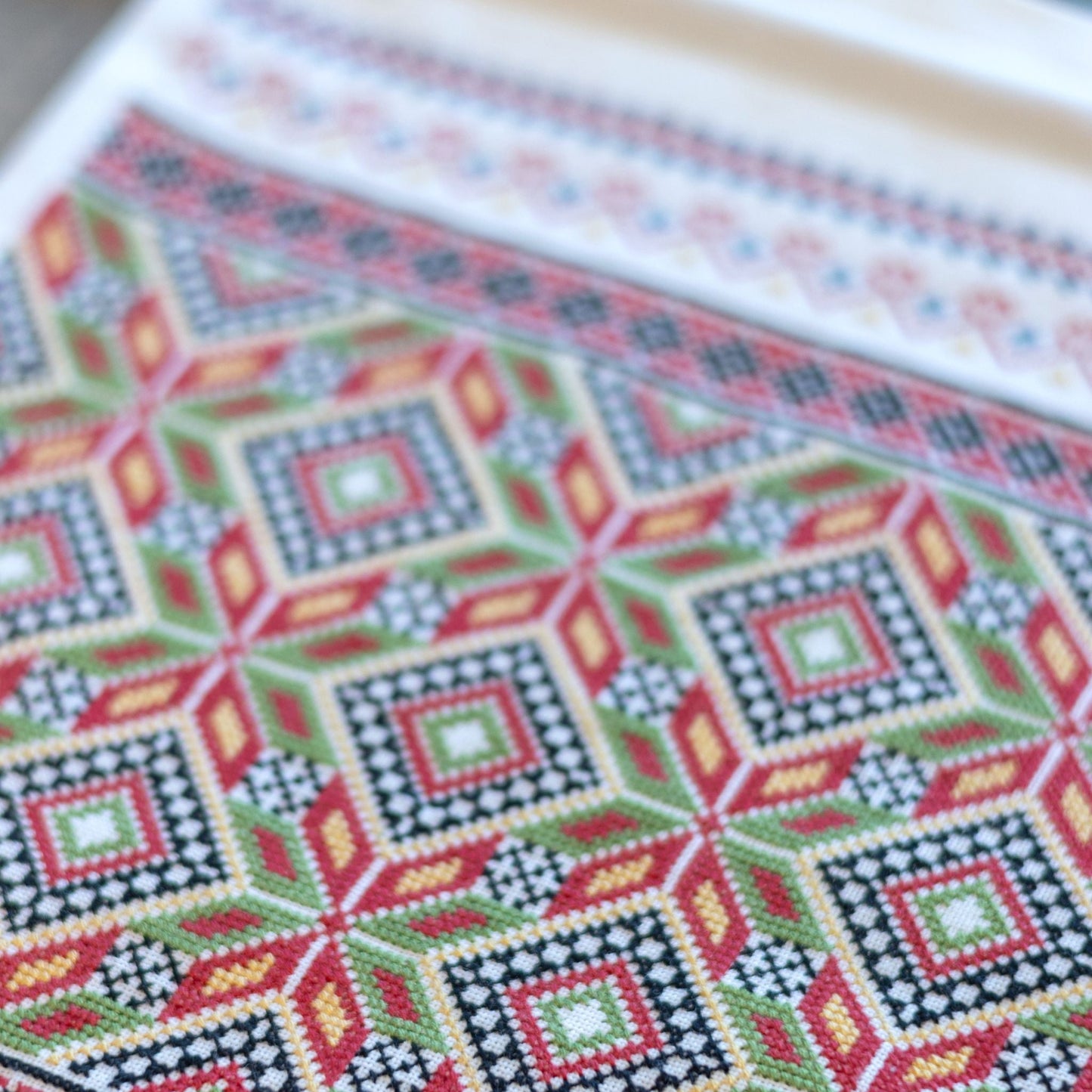 Close-up of a cross-stitched pattern with geometric design on fabric.