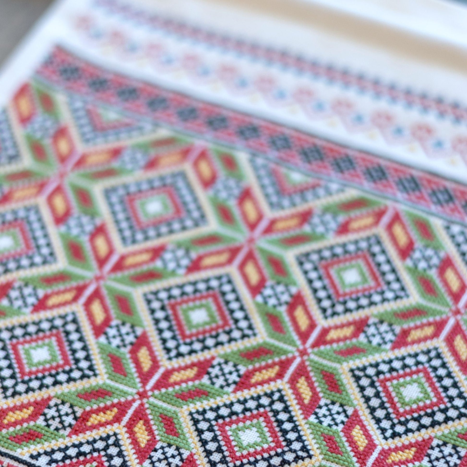 Close-up of a cross-stitched pattern with geometric design on fabric.