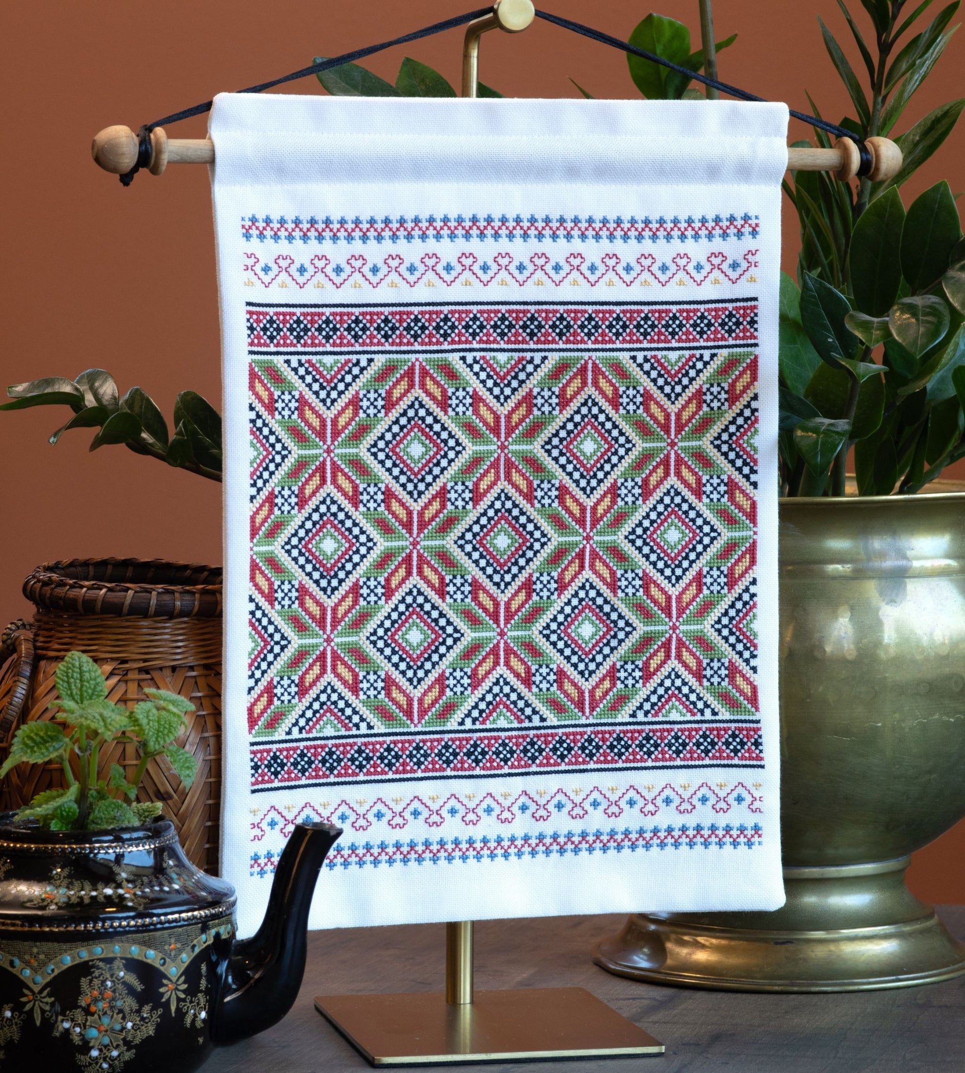 Cross stitch folk embroidery wall hanging with geometric pattern on a stand