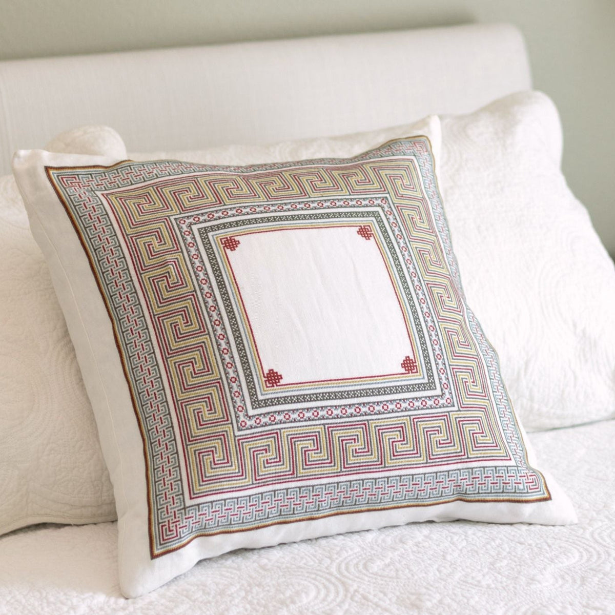 Somerset Meander cross stitch folk embroidery cushion cover with its perimeter meander border in terra cotta and warm blue
